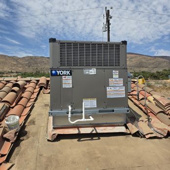 York HVAC unit on a tiled roof with mountains and blue sky in the background.