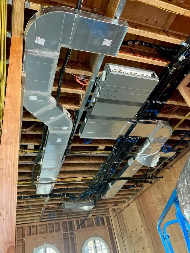 HVAC ductwork and electrical wiring installed in a wooden ceiling.