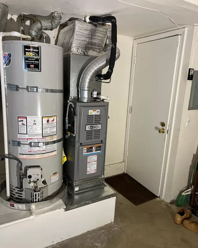 Water heater and furnace in a utility room next to a closed white door.