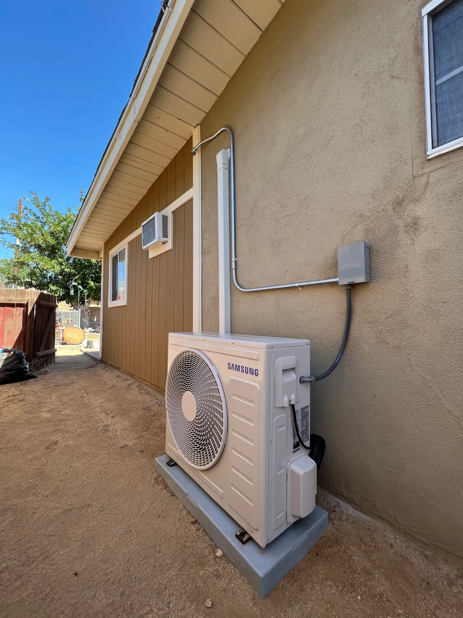 Air conditioner unit on a roof, blue sky backdrop, desert landscape in the distance.
