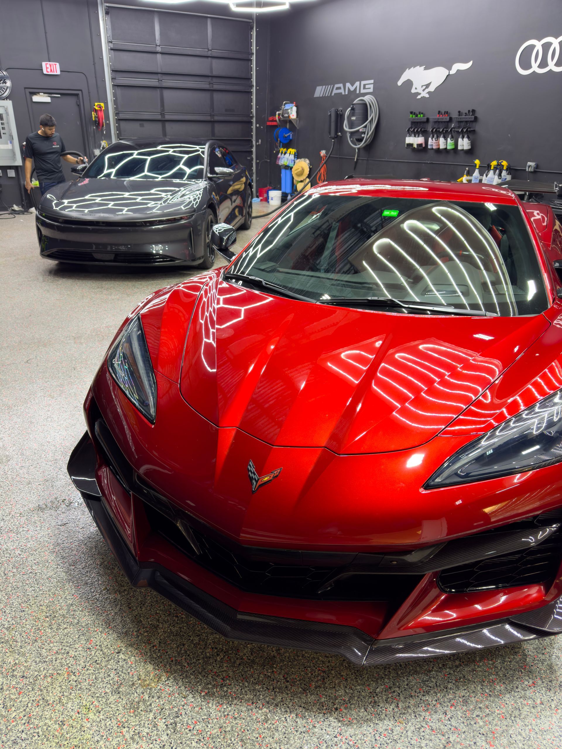 Red Corvette and gray Dodge Charger in a garage.