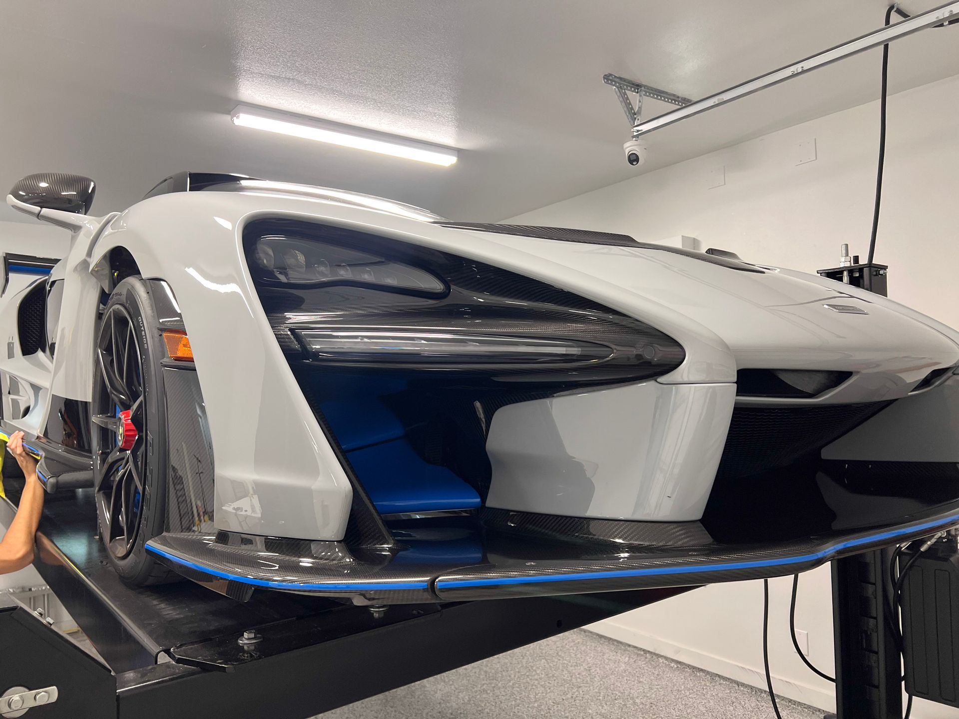 White McLaren Senna sports car on a lift in a garage.