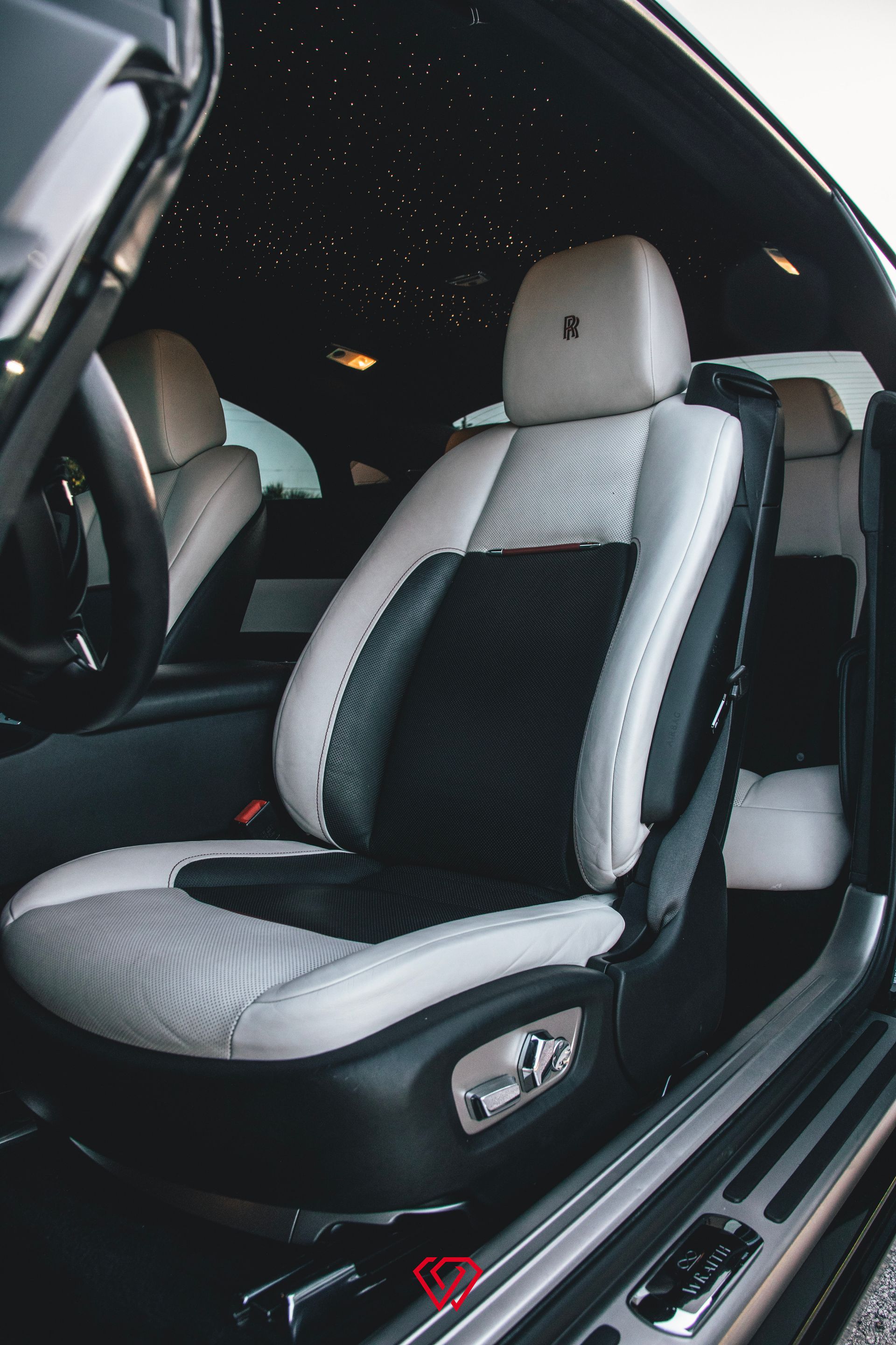 Luxurious car interior with black, white, and gray leather seats. The ceiling has embedded star lights.