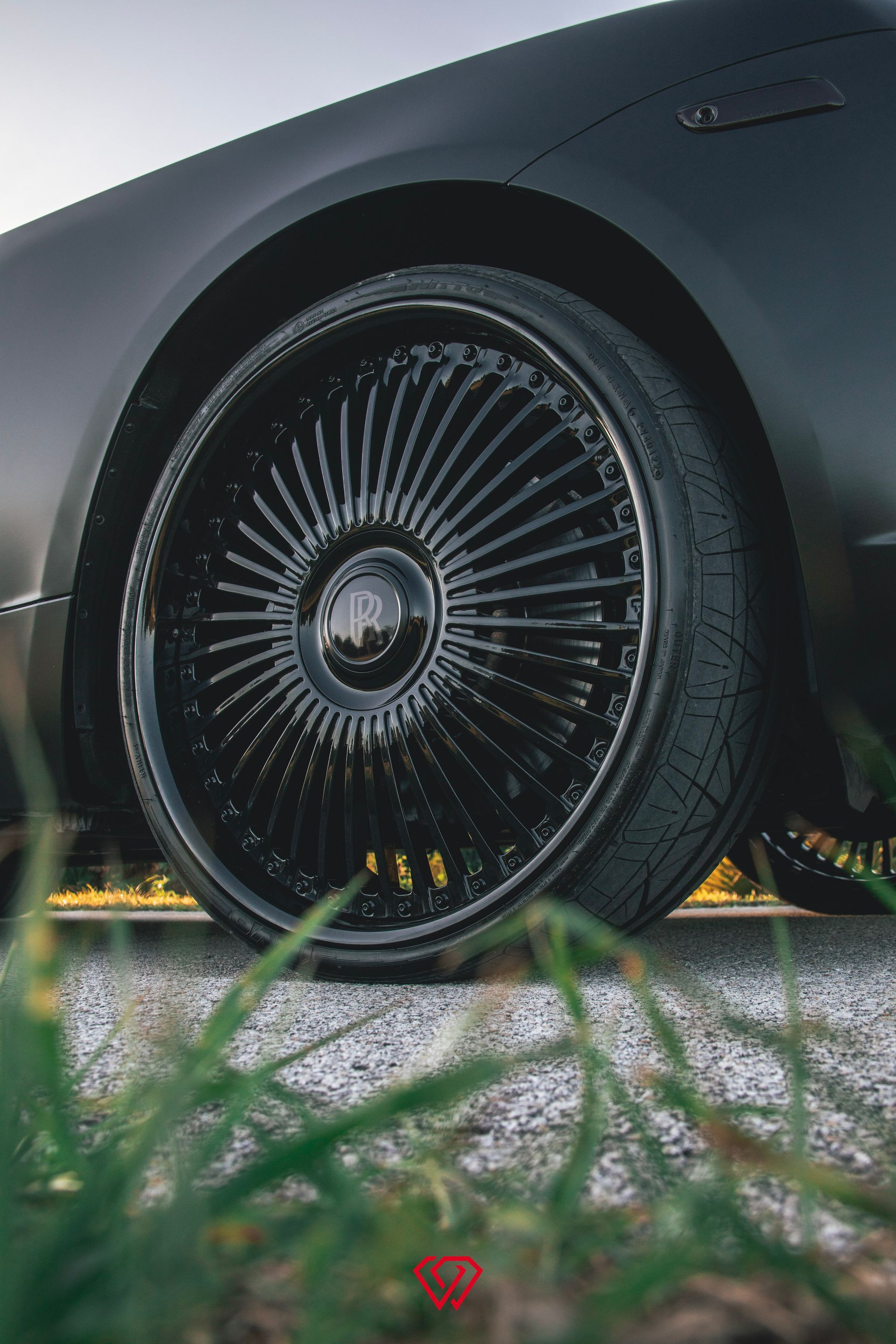 Black car wheel with intricate spoke design; low angle shot.