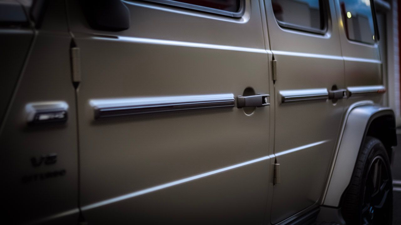 Tan Mercedes-Benz G-Wagon SUV, chrome accents, side view.