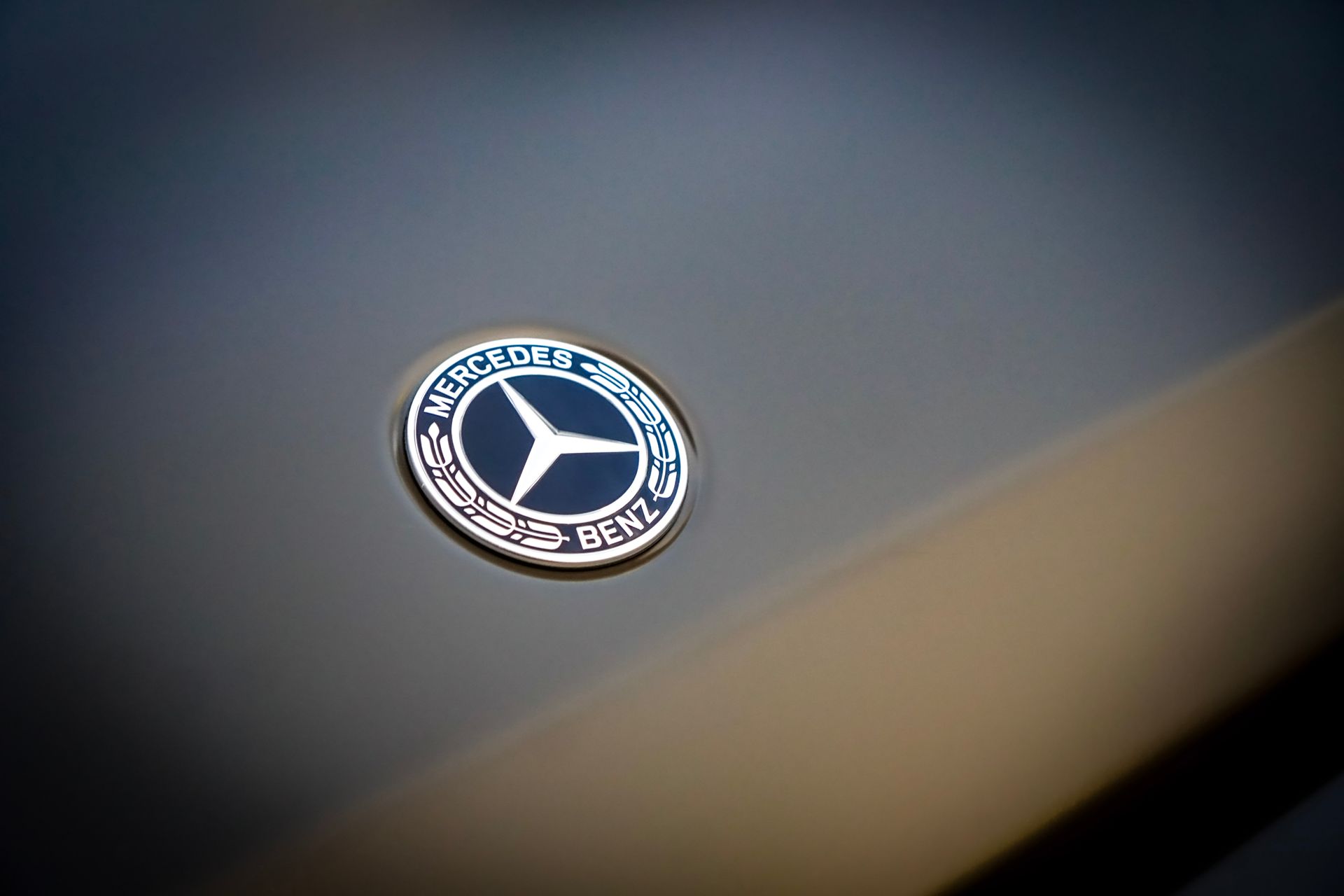 Mercedes-Benz emblem on a dark grey car surface, with a three-pointed star inside a circle.