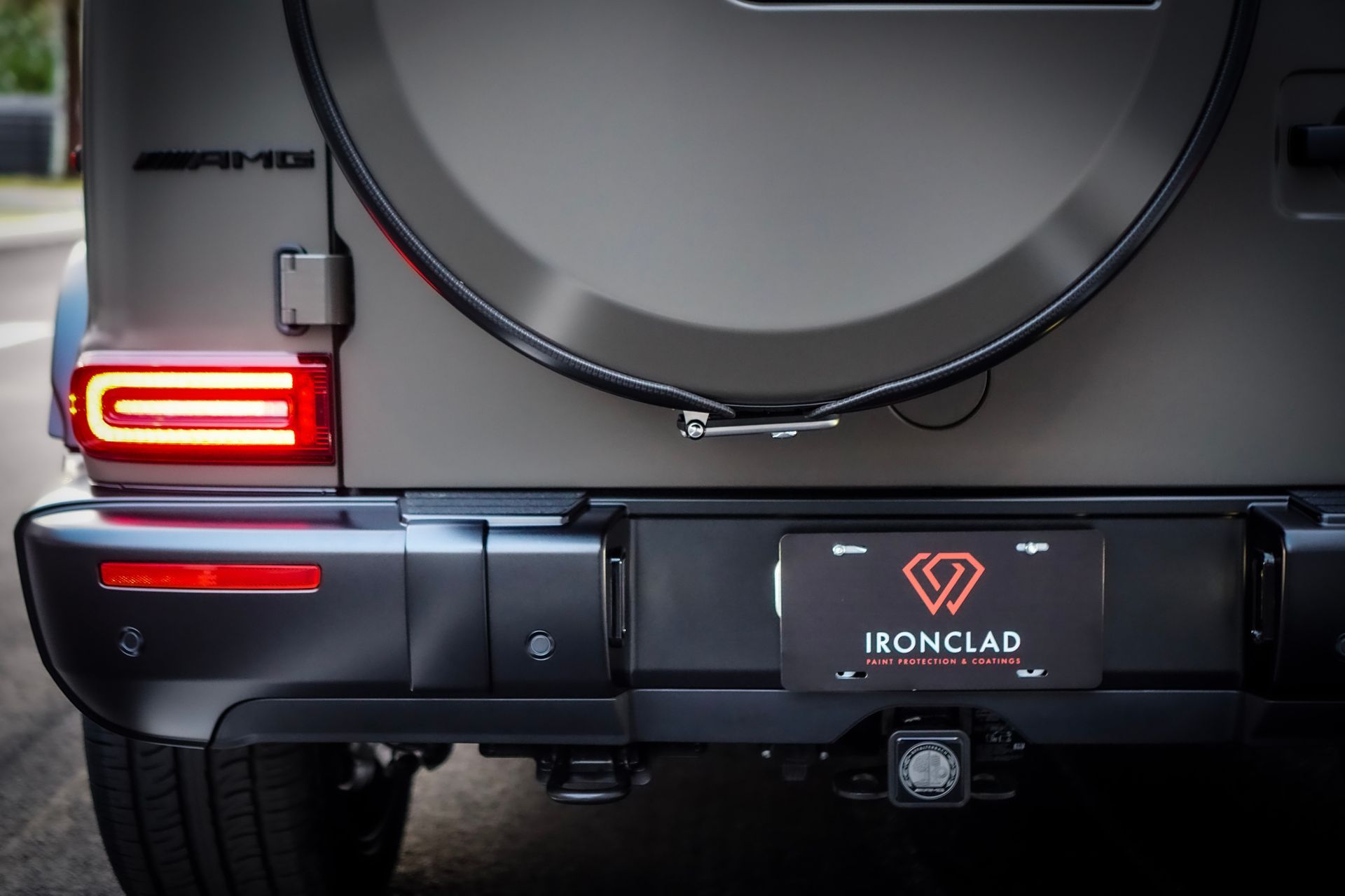Rear view of a matte gray Mercedes-Benz G-Wagon SUV with a spare tire, taillight, and license plate.