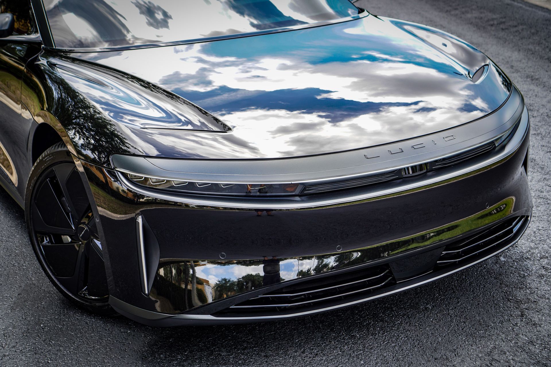 Black Lucid Air electric vehicle; front view showing headlights, glossy finish, and asphalt road.