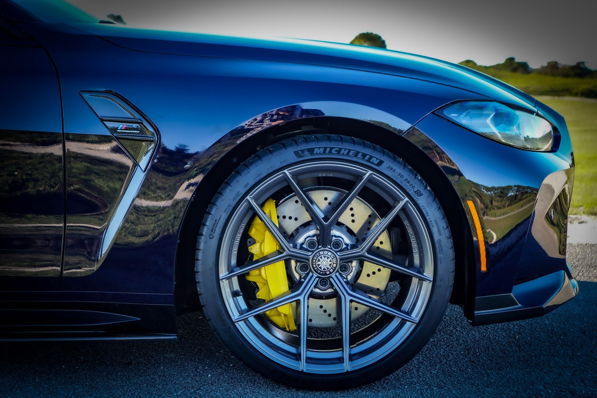 Dark blue sports car wheel with yellow brake calipers.