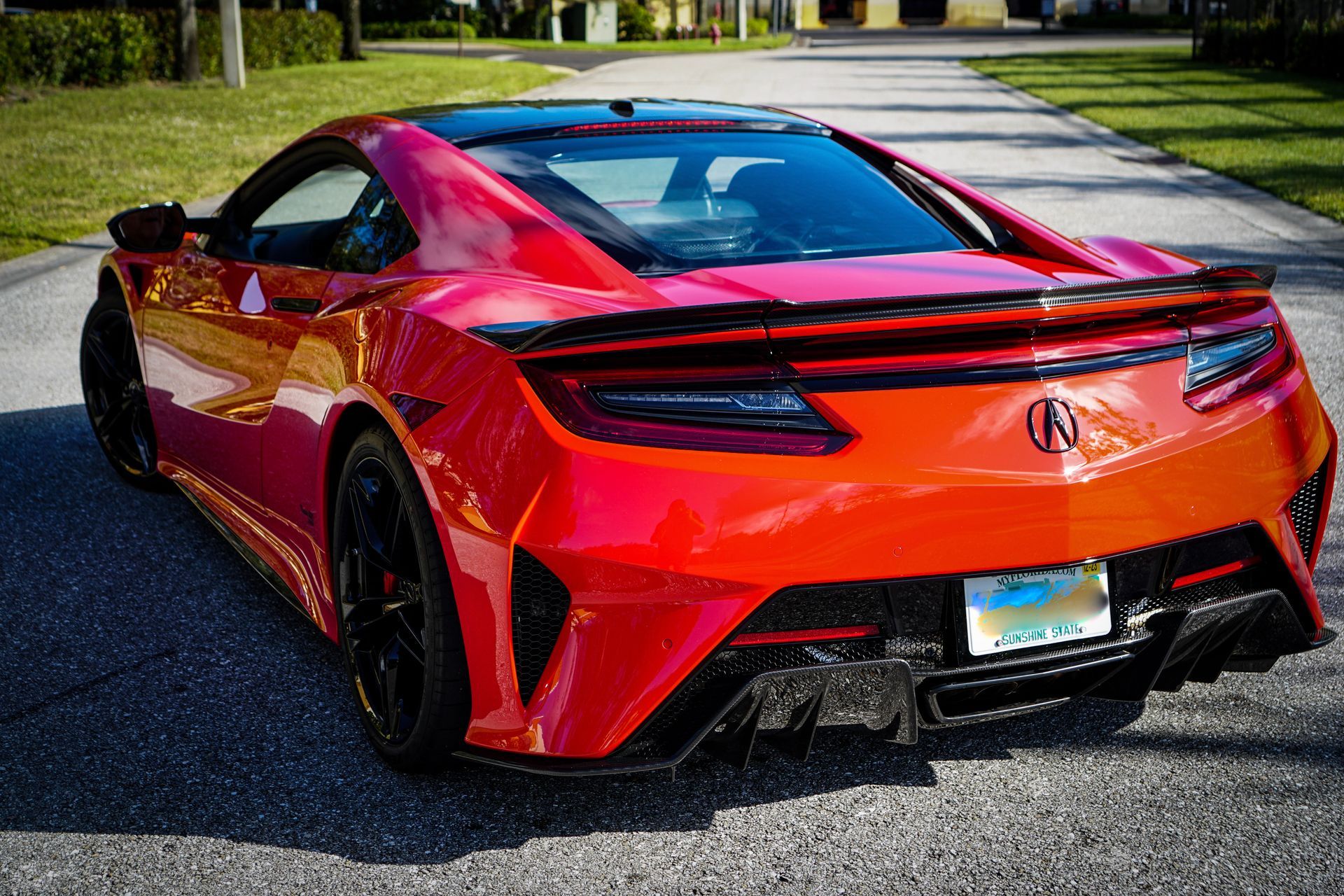 Red Acura NSX sports car parked on an asphalt driveway.