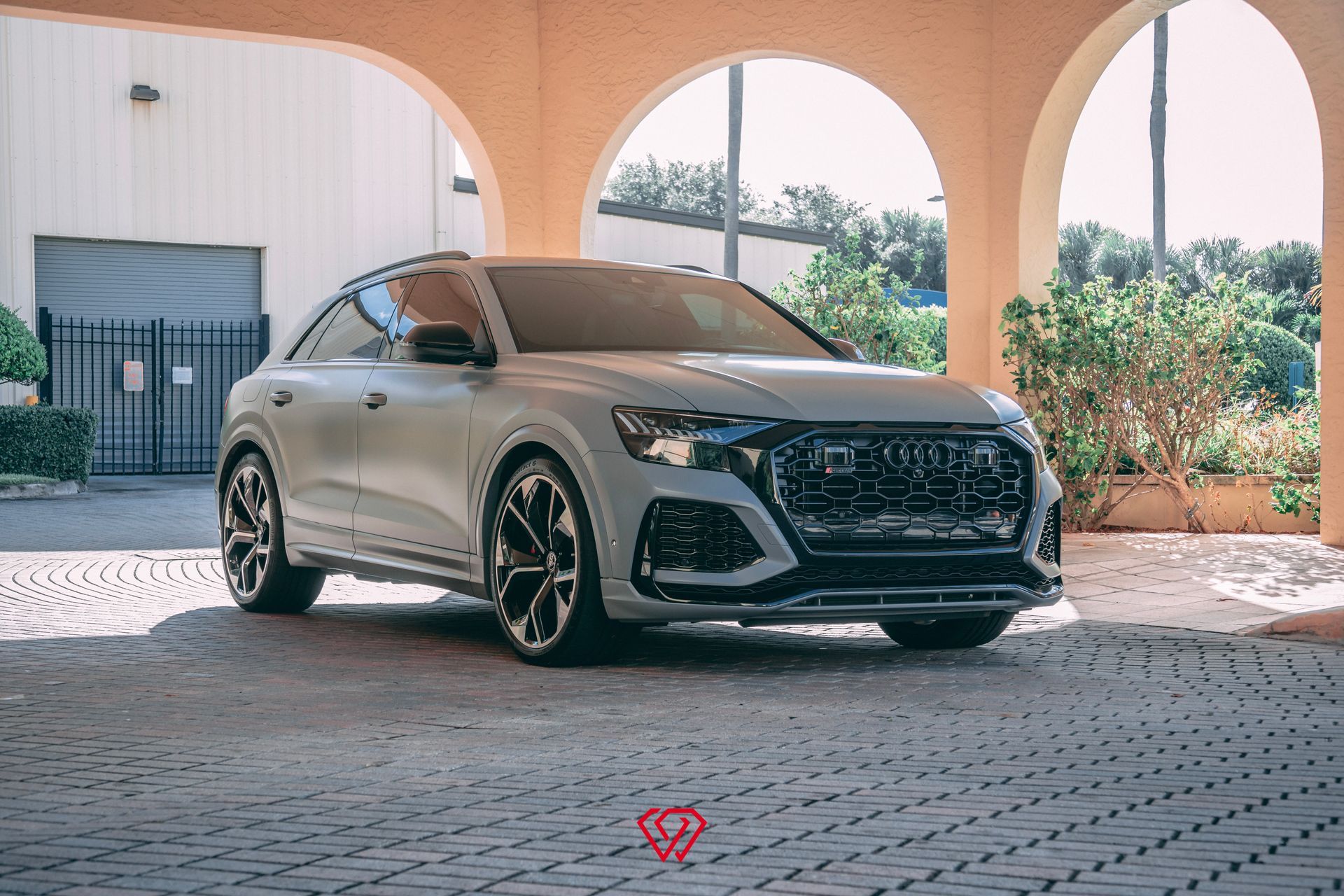 Silver Audi RS Q8 SUV parked under an arched structure with a paved driveway.