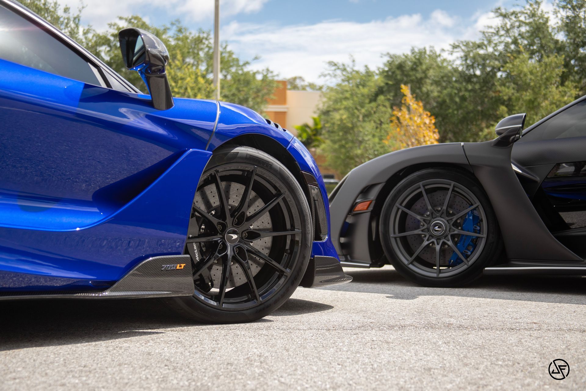 Blue and black McLaren sports cars parked side-by-side on an asphalt surface.
