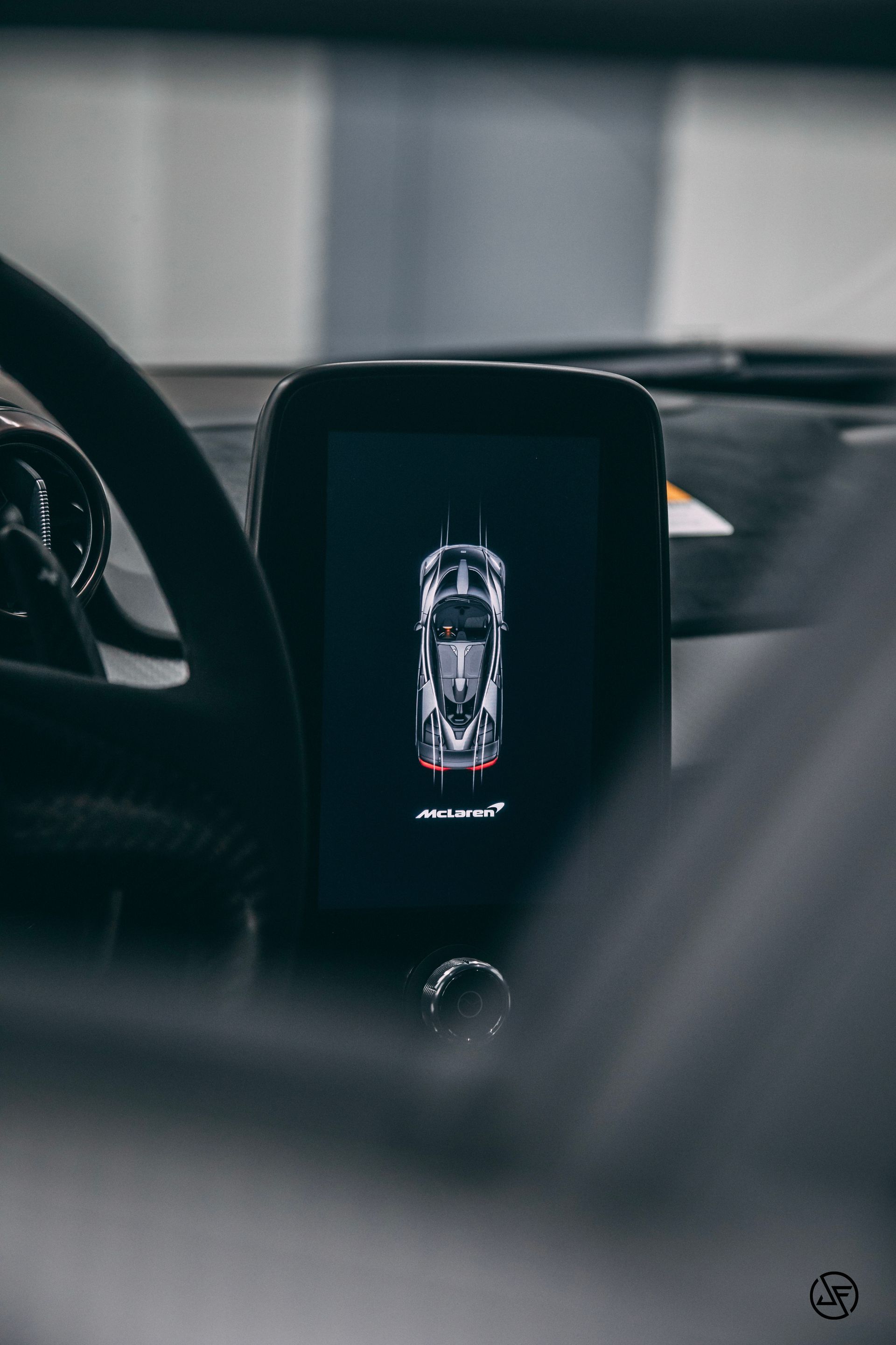 McLaren car dashboard display shows a top-down view of the car; black and white scheme, interior view.