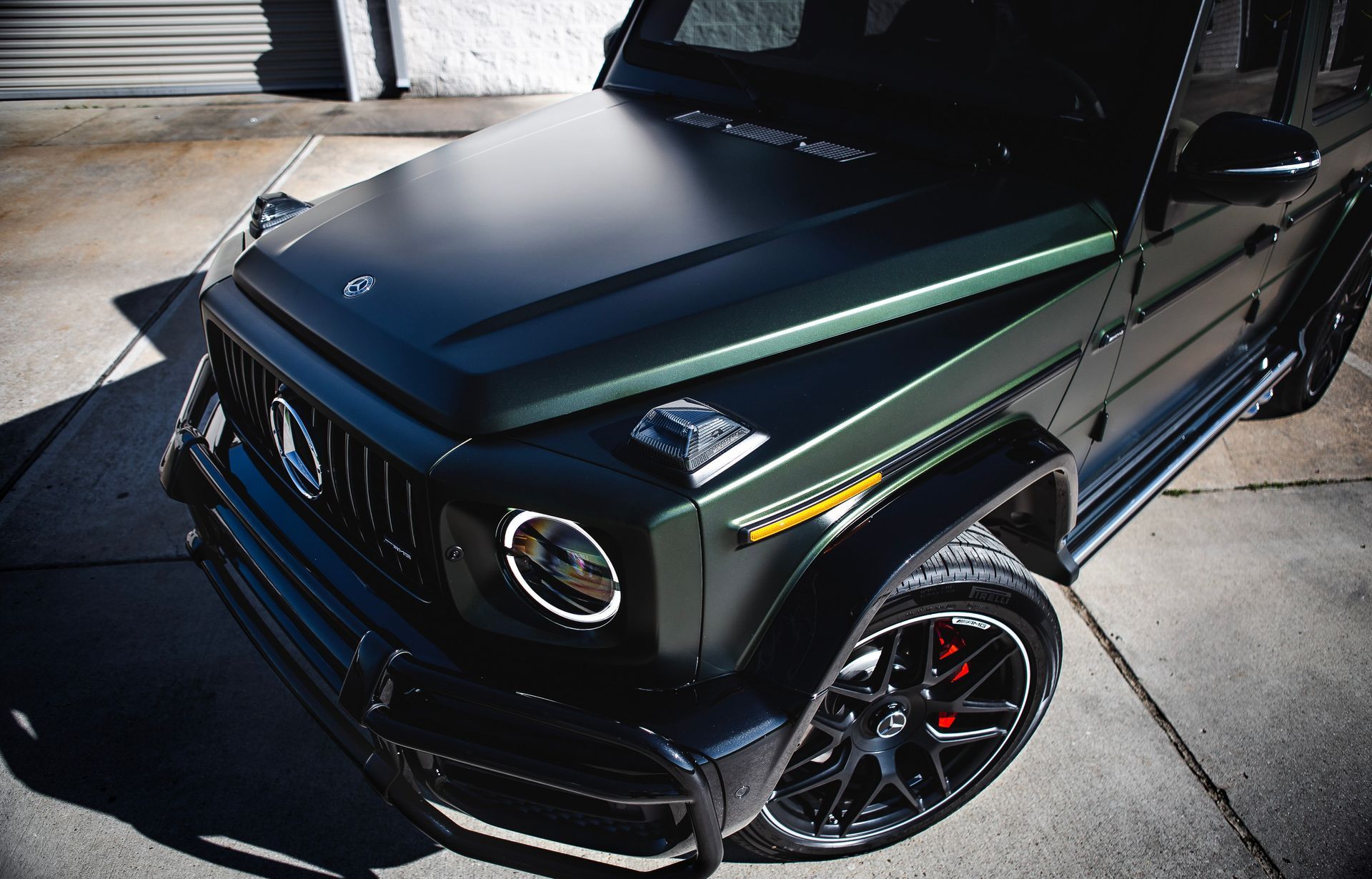 Dark green Mercedes-Benz G-Wagon SUV parked outside with black rims.