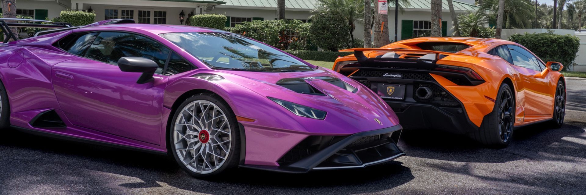 Purple Lamborghini and orange McLaren parked side-by-side on an asphalt road.