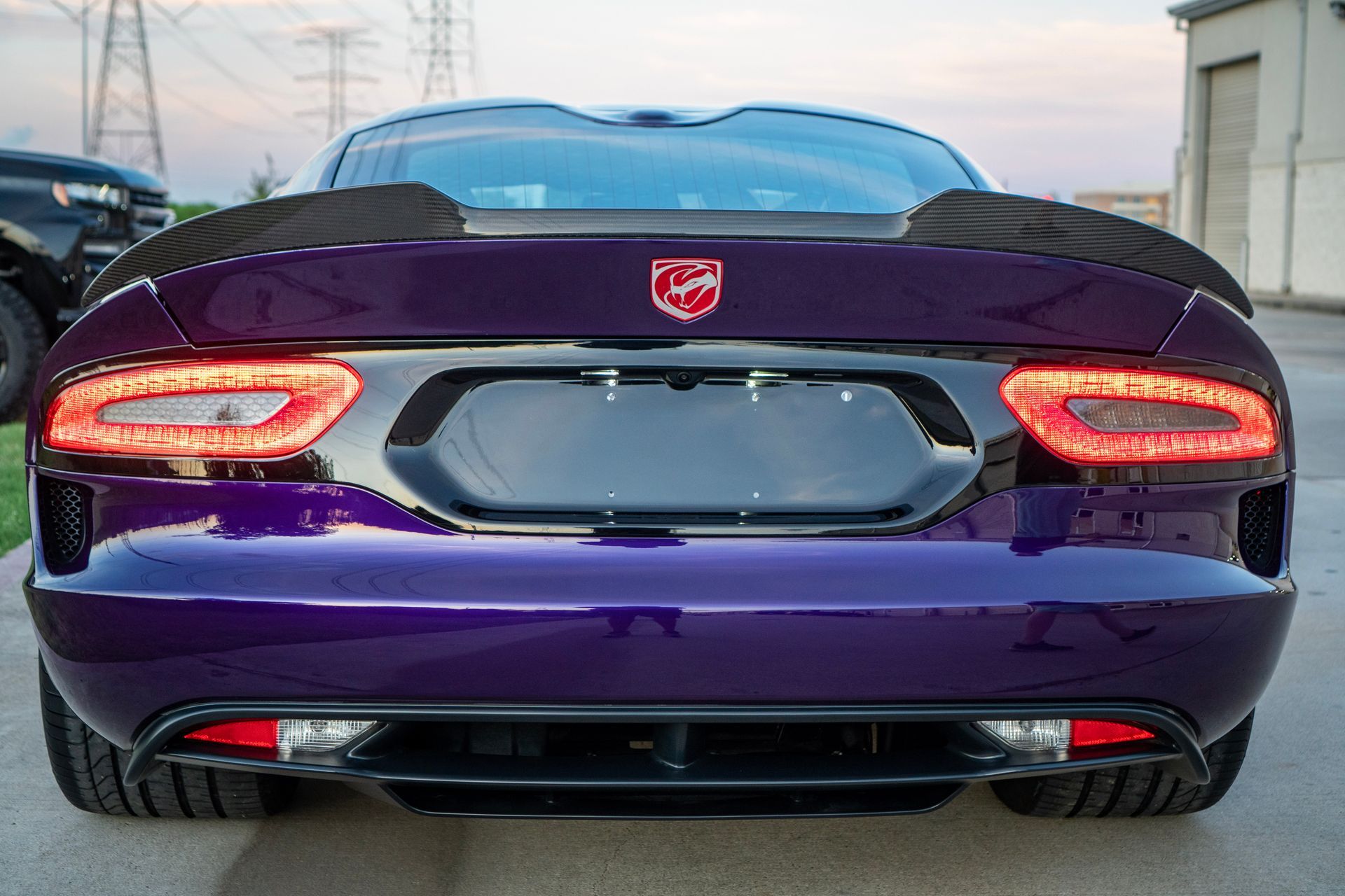 Purple Dodge Viper sports car rear view with spoiler, taillights, and logo.