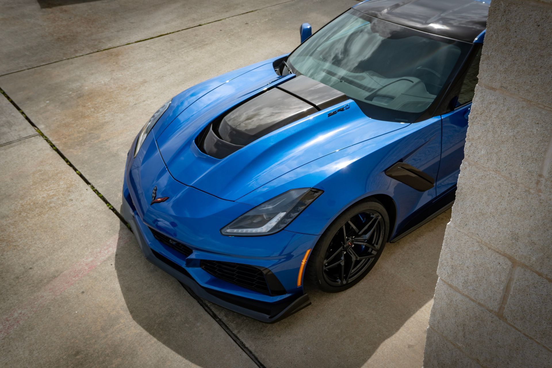 Blue sports car with black accents parked on concrete.