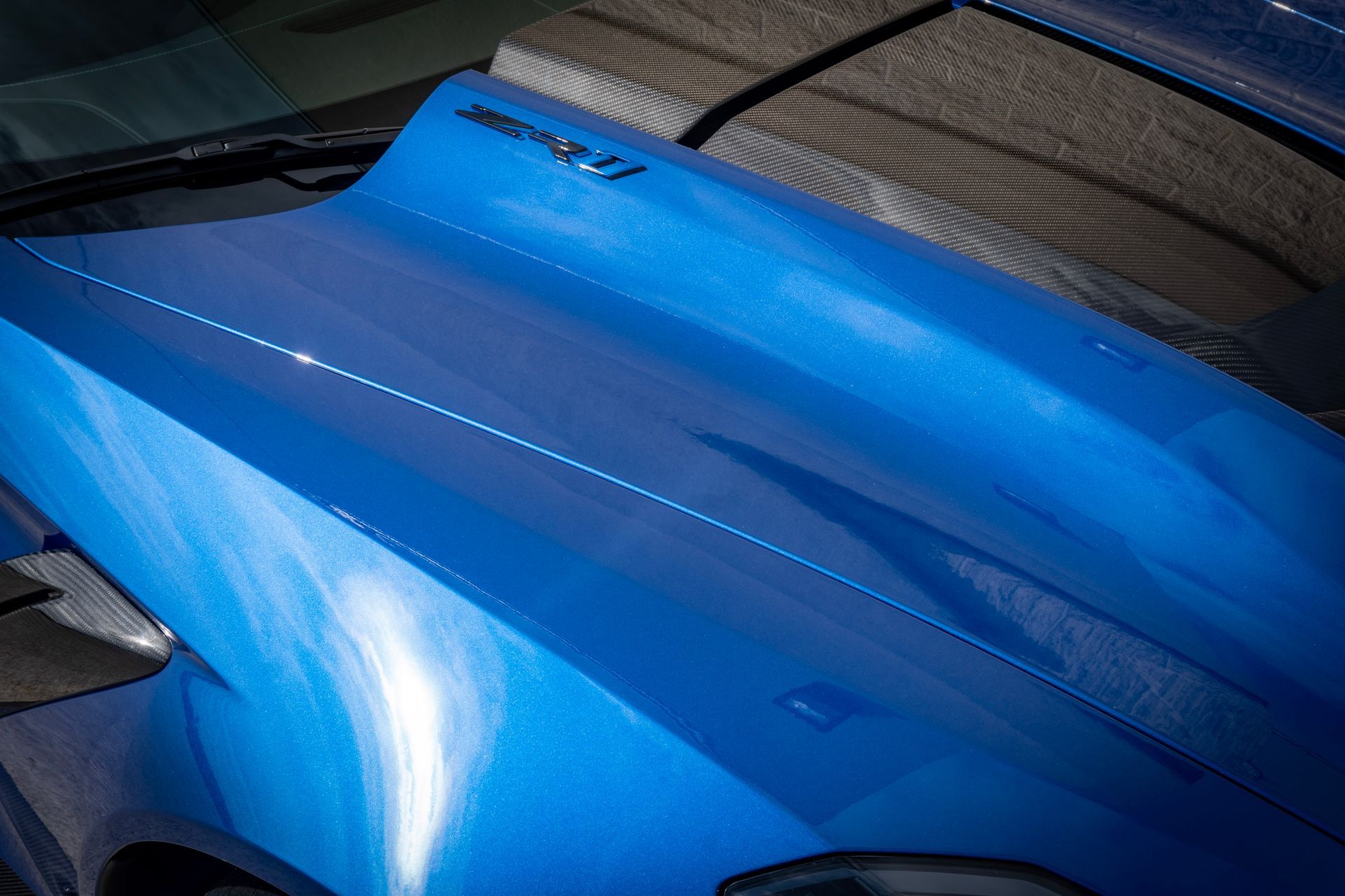 Blue car hood with a raised section, shiny finish.