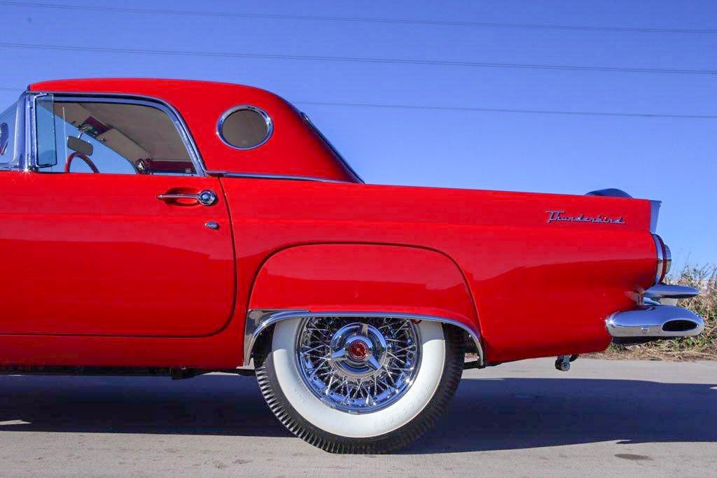 Red vintage Ford Thunderbird with white-walled tires, chrome accents, and a porthole window.
