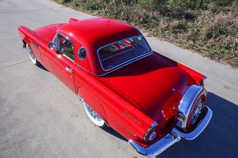 Red vintage Ford Thunderbird with a hardtop parked on a road.