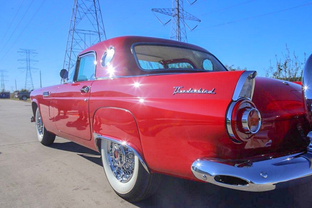 Red 1955 Ford Thunderbird, rear view, chrome trim, whitewall tires, parked outside on a sunny day.