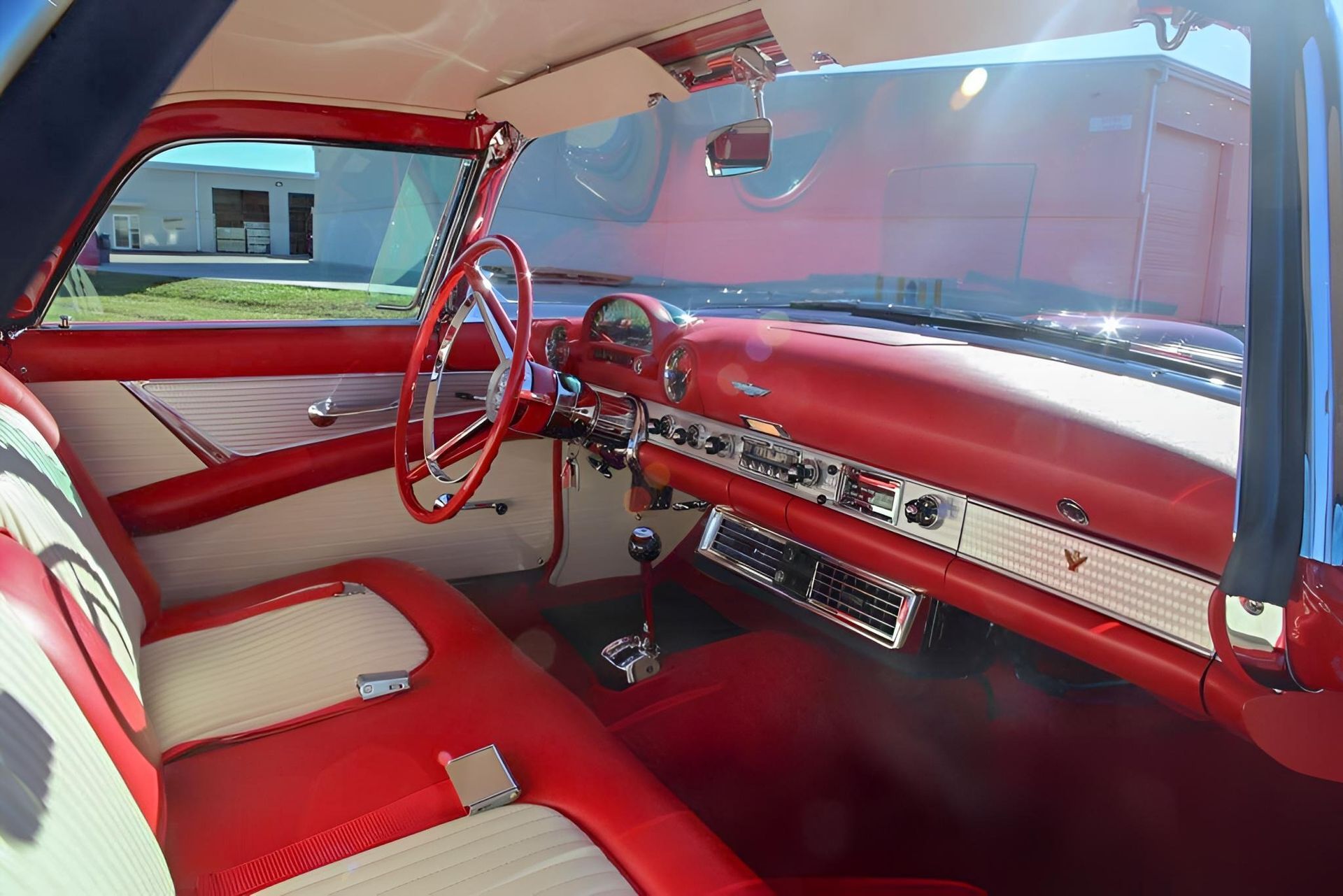 Red and white interior of a classic Ford Thunderbird. Features a red dashboard, seats, and steering wheel.