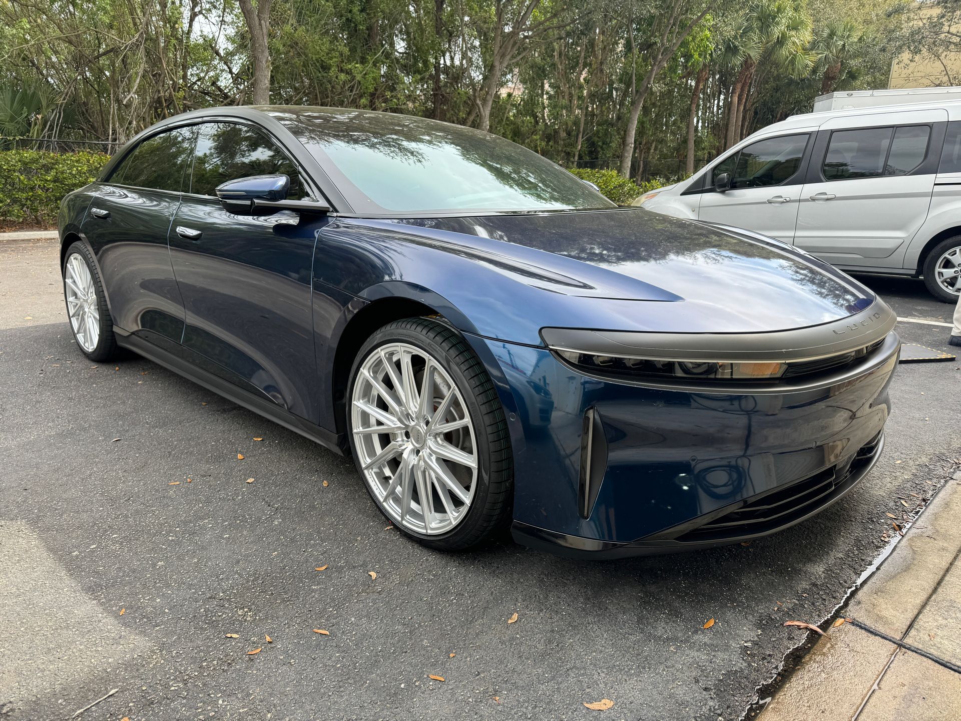 Blue Lucid Air electric sedan parked on asphalt; silver wheels, sunny day.