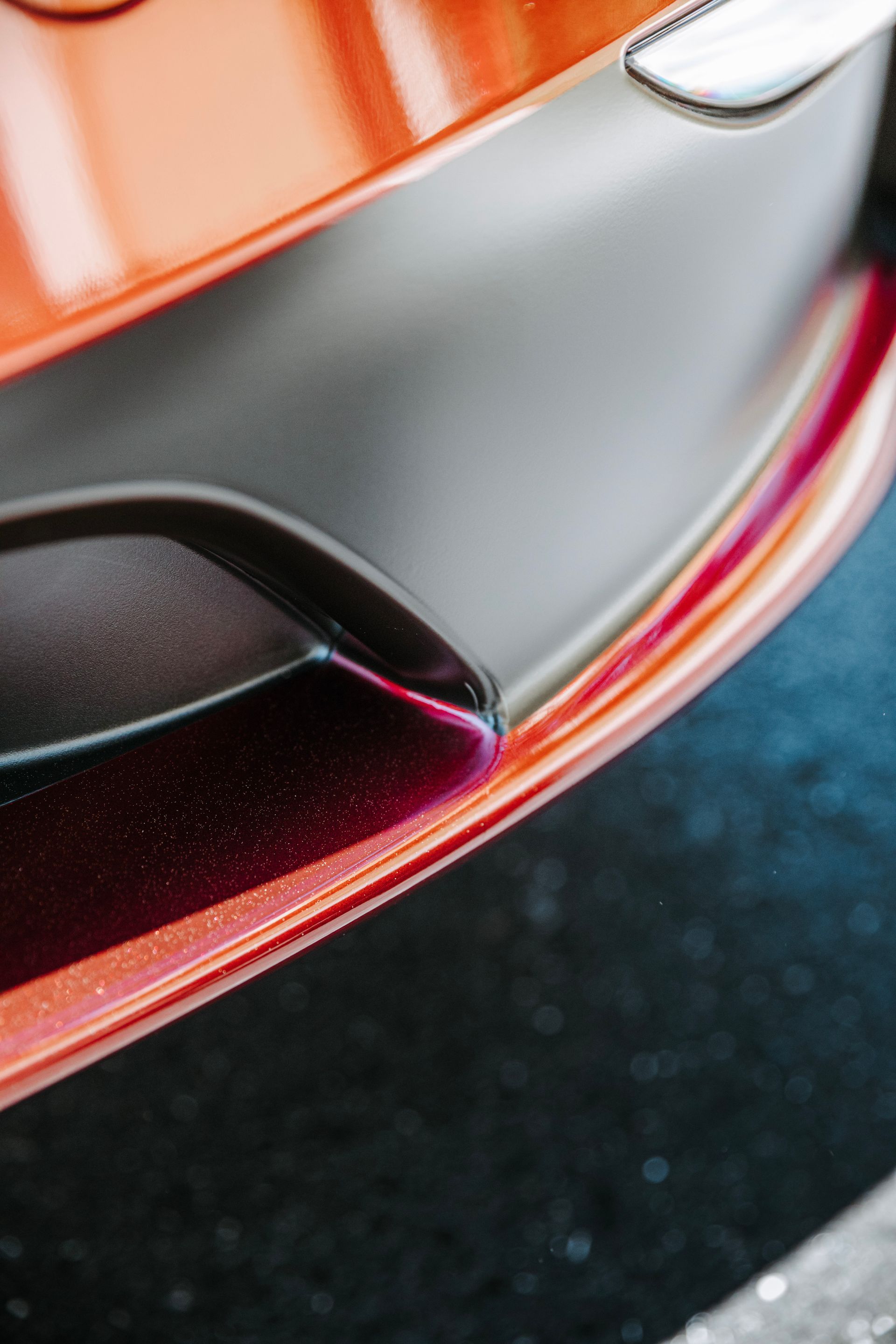 Close-up of a car bumper in orange, gray, and black.