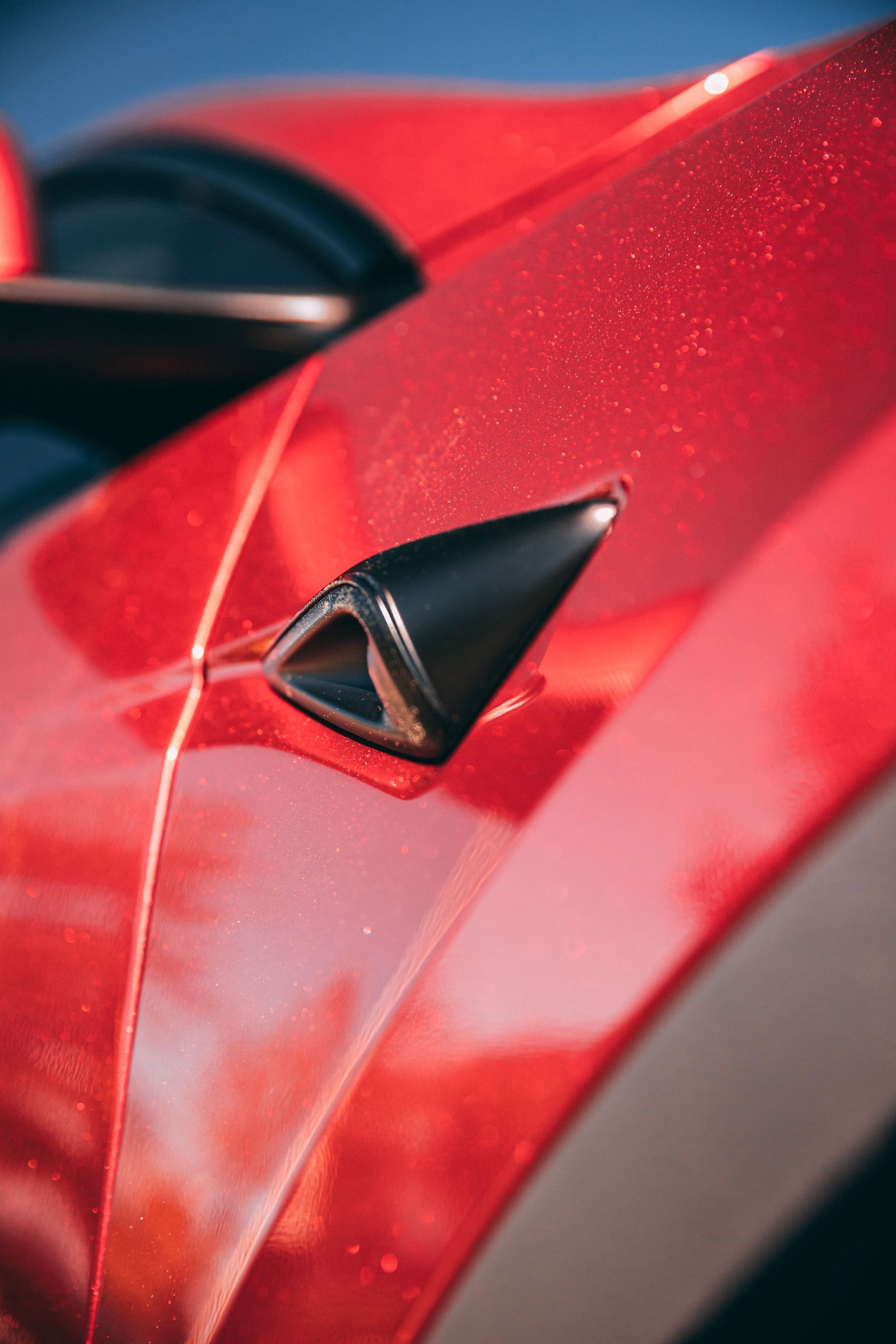 Close-up of a red car's side, showing a black side camera.