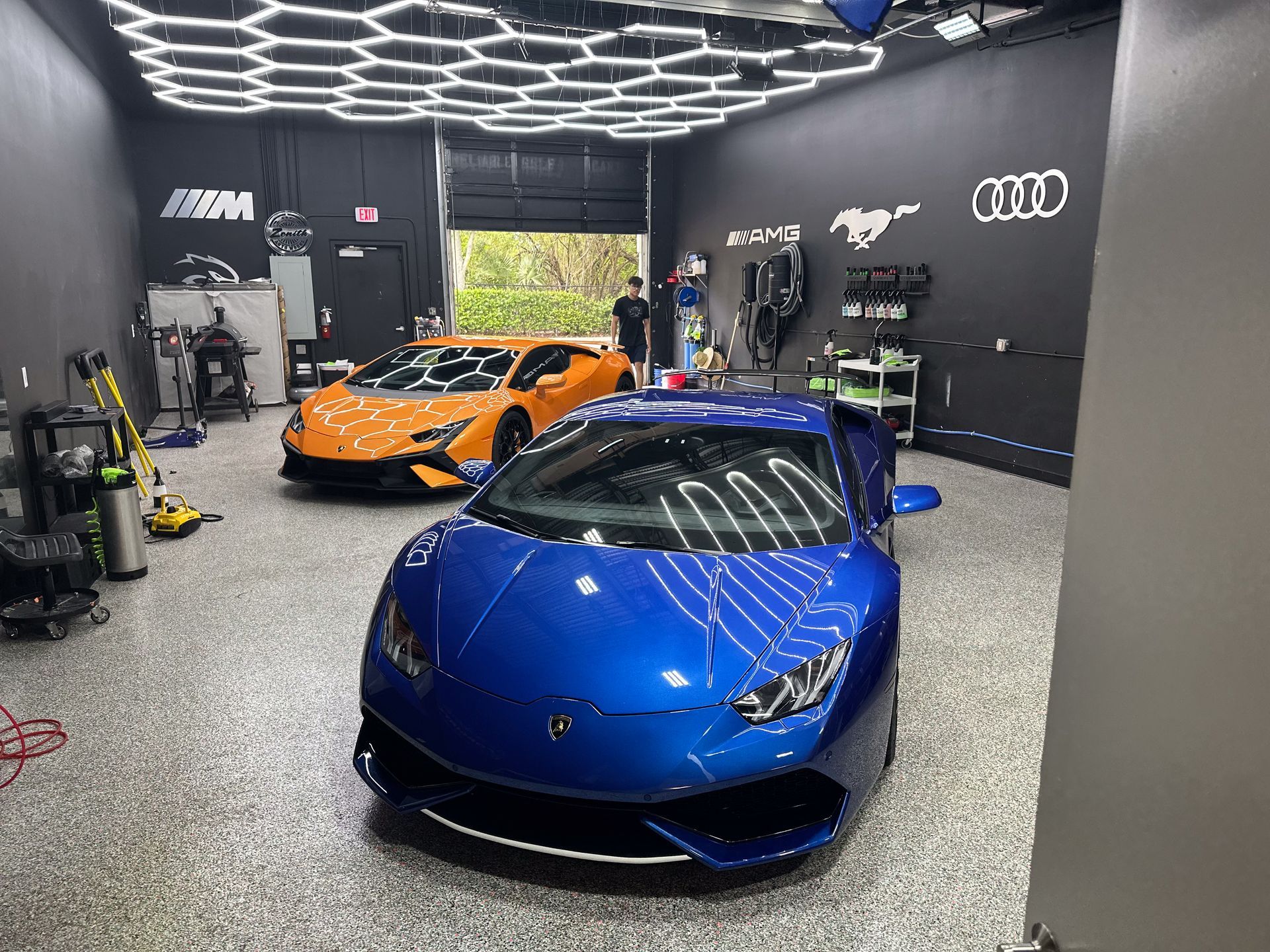 Blue and orange Lamborghini cars in a car detailing garage with hexagon lights.