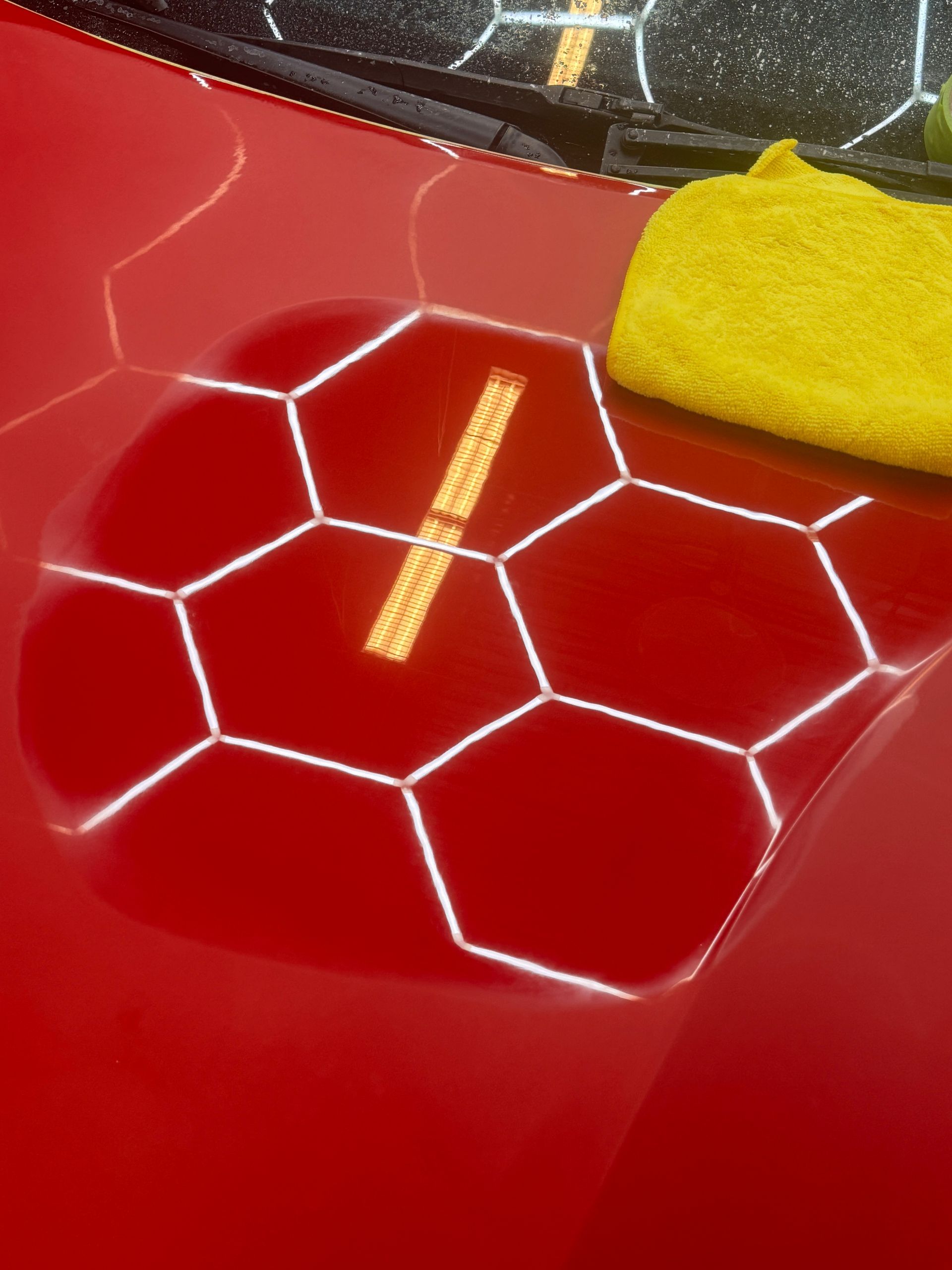 Red car hood with a honeycomb pattern and yellow cloth.
