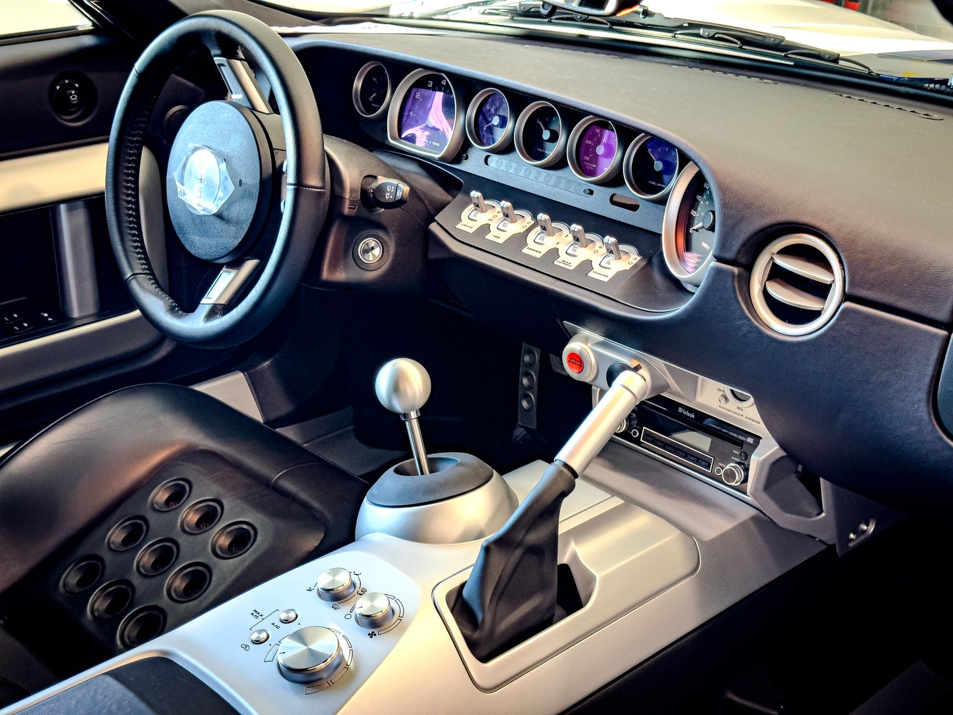 Interior of a Ford GT sports car, black and silver dashboard, steering wheel, and gear shift.