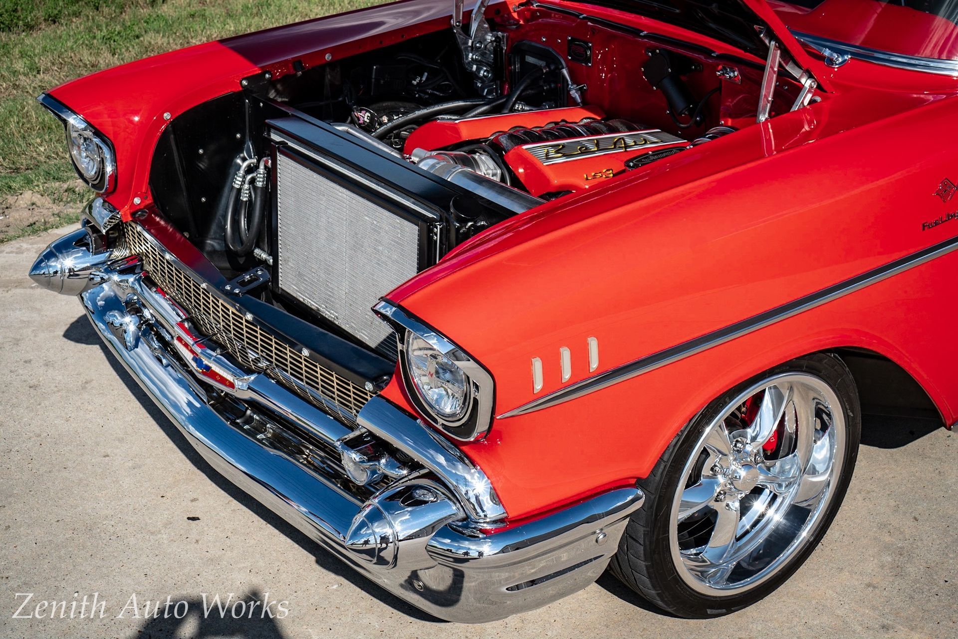 Red classic car with chrome details, engine visible, parked outdoors.