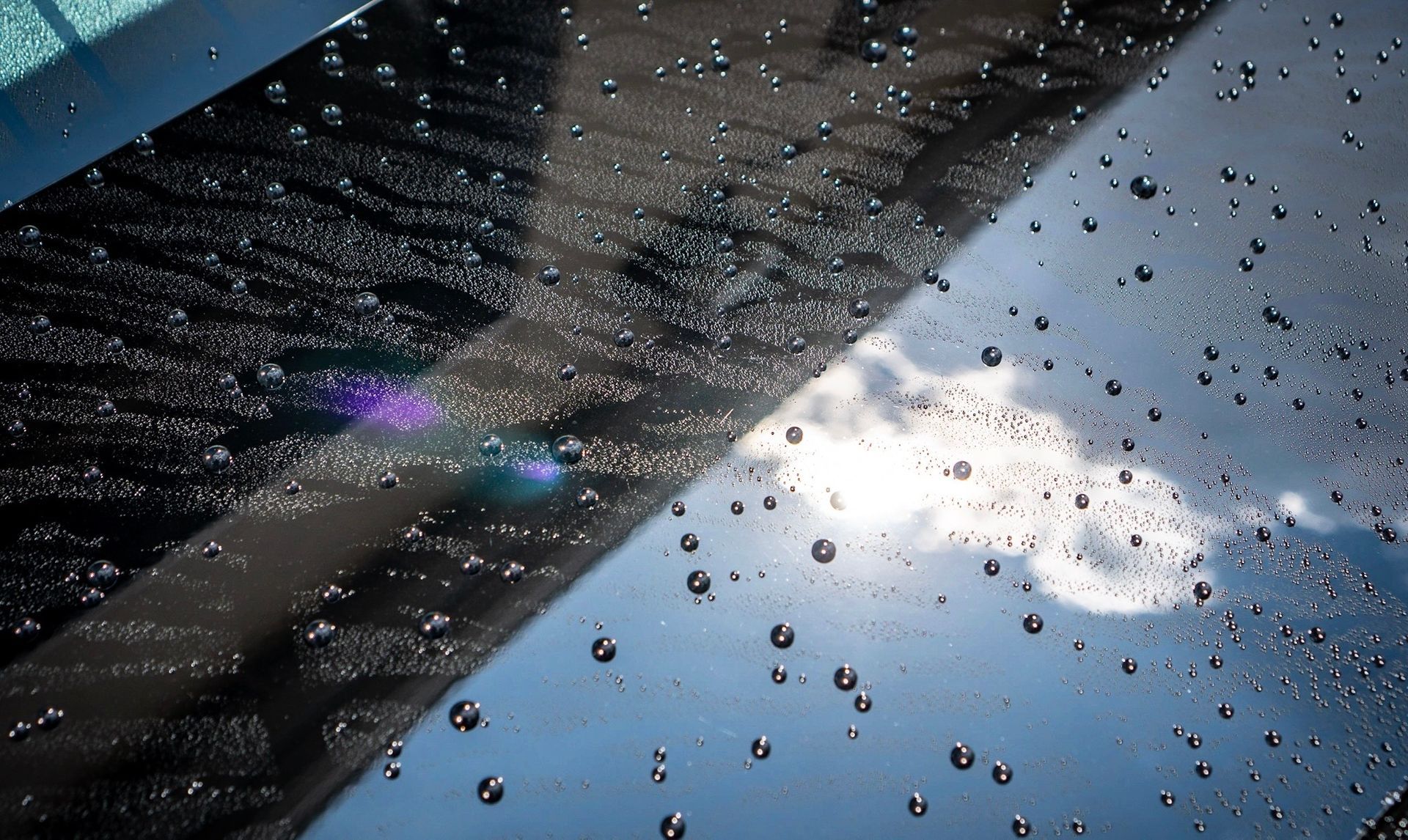 Water droplets on glass with a sky reflection.
