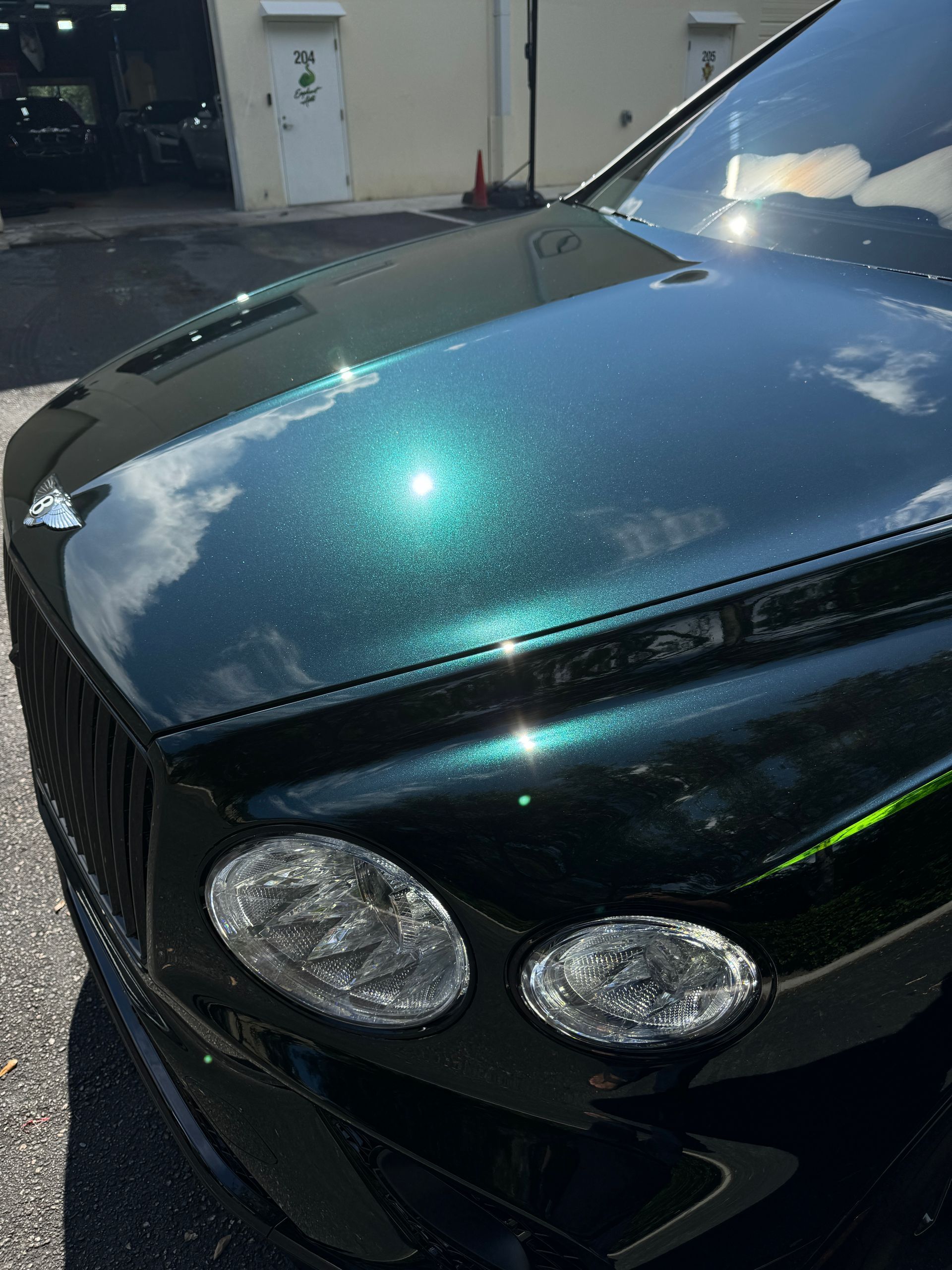 Green Bentley car with sparkling paint, front view.