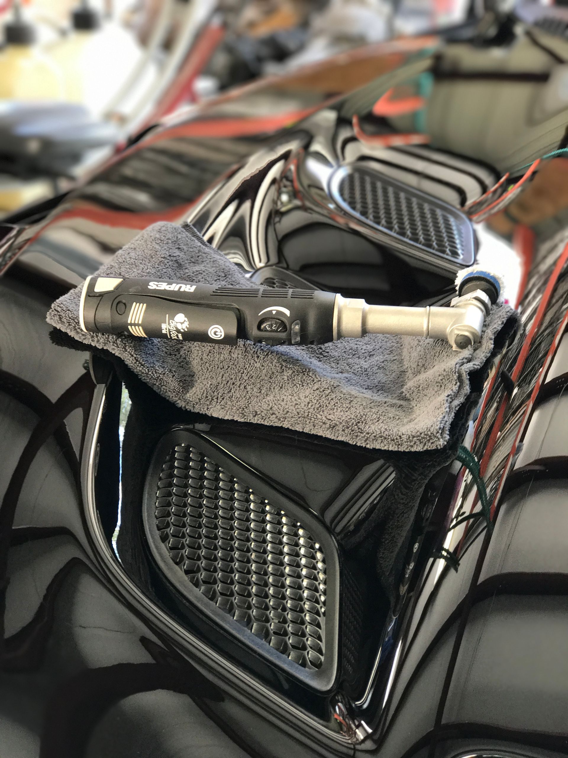 Black motorcycle with a detailing tool resting on a microfiber cloth.