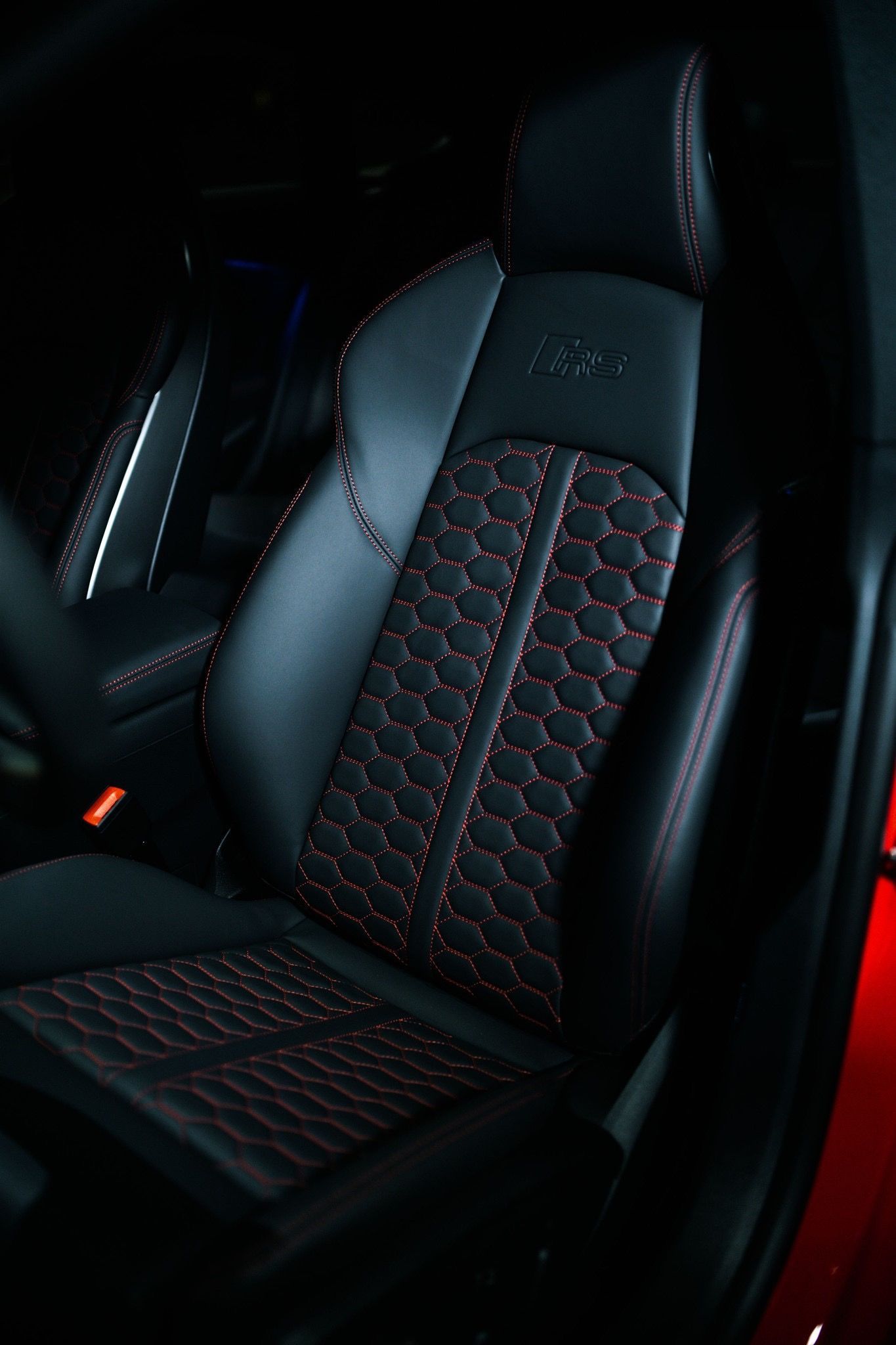 Black leather car seat with red stitching, the seat back has 