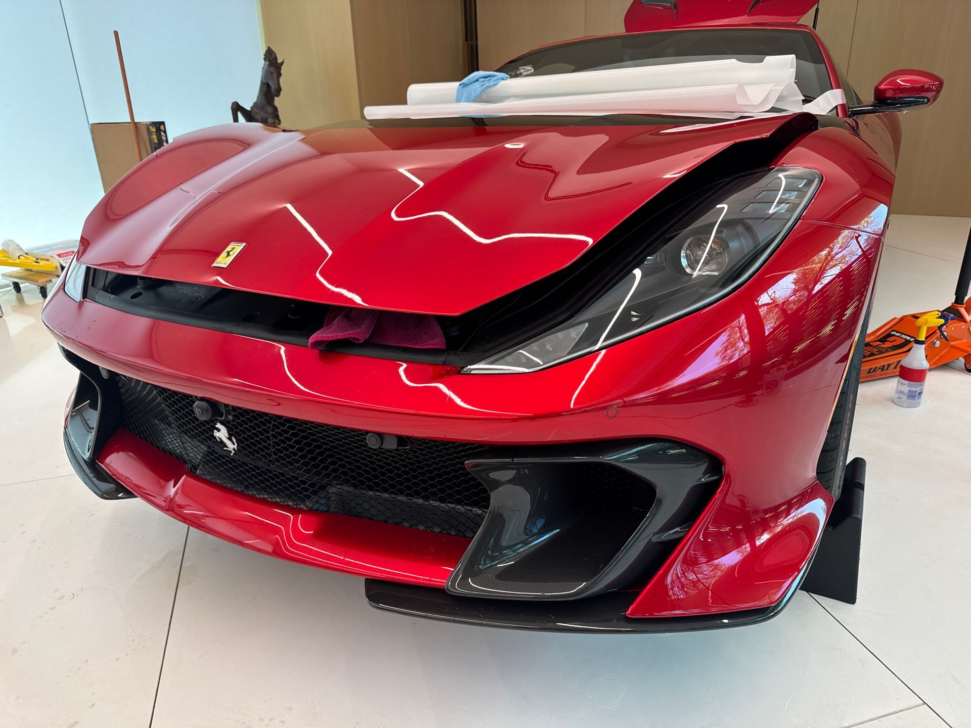Red Ferrari sports car with black accents in a showroom.