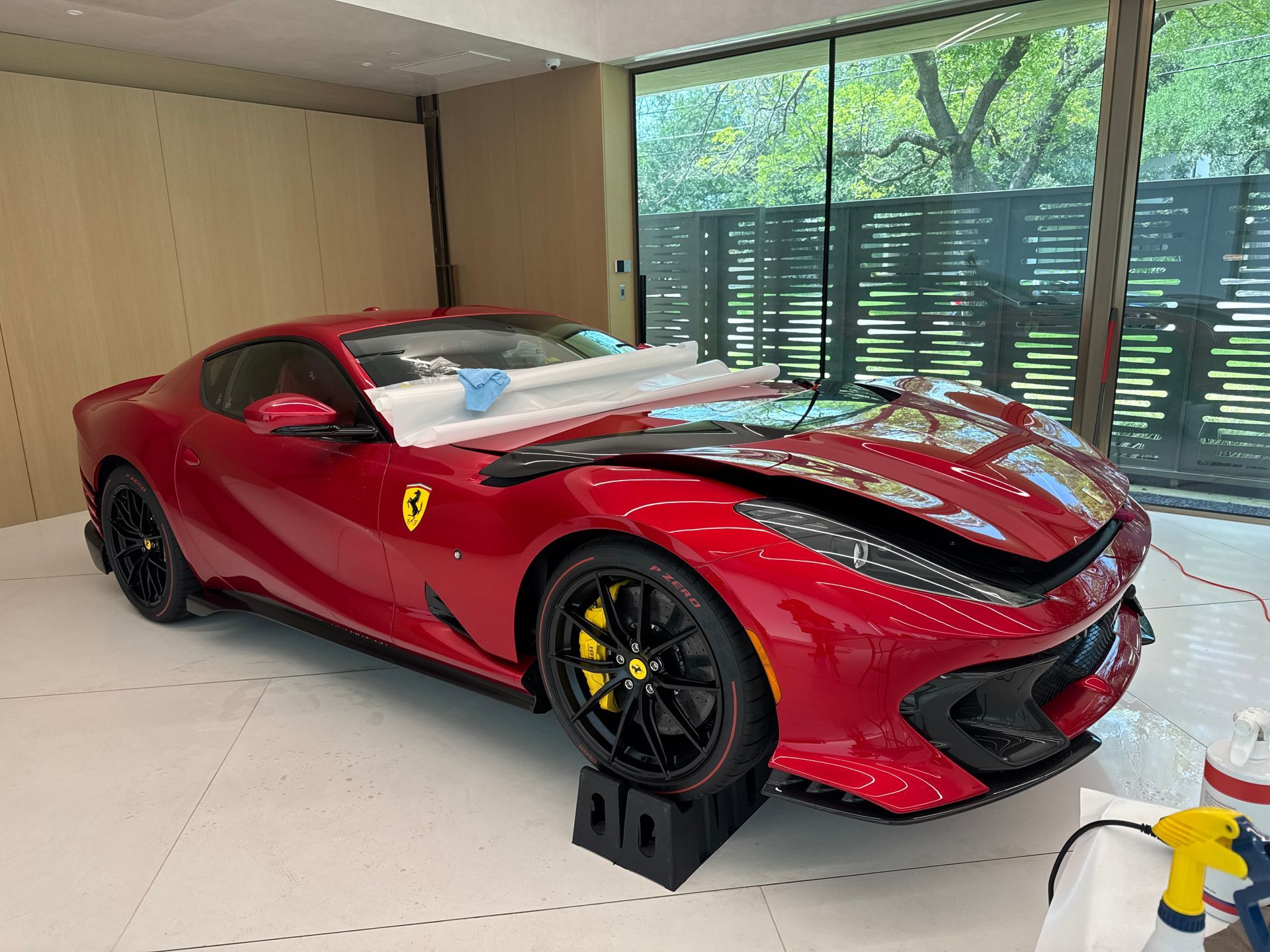 Red Ferrari 812 Superfast in a garage, possibly getting maintenance.