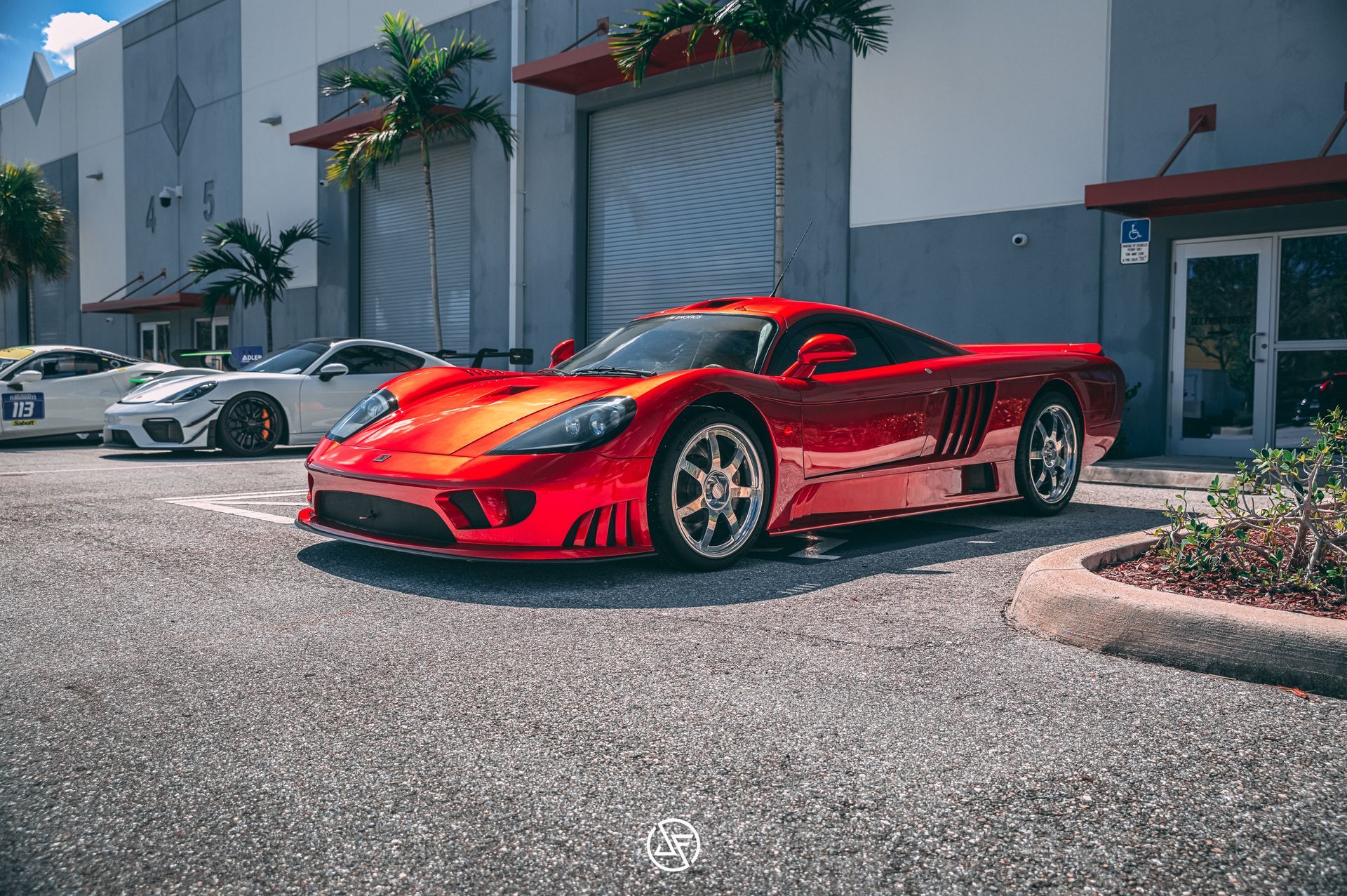 Red Saleen S7 parked in front of a building with other cars visible in the background.