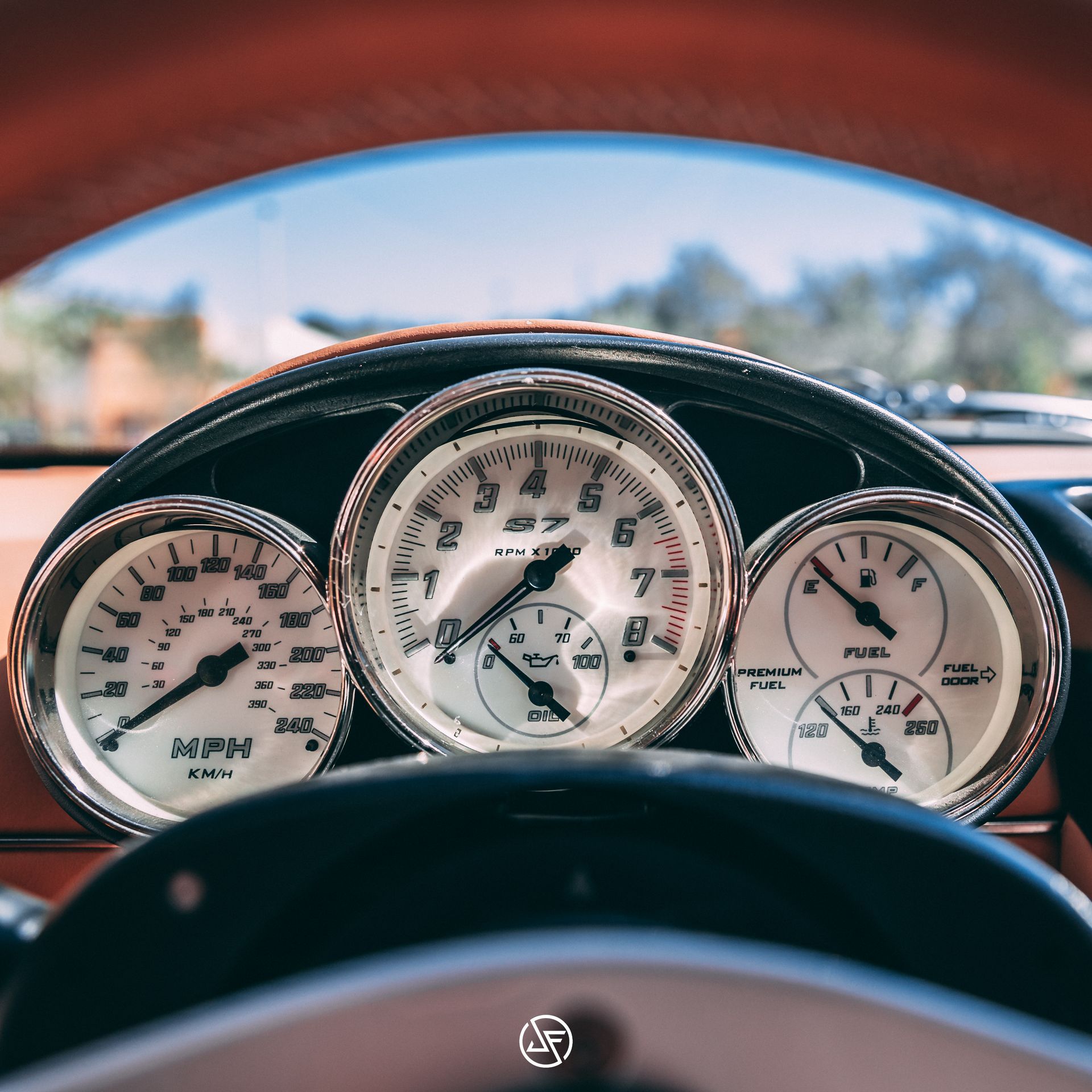 Dashboard gauges in a classic car, showing speedometer, RPM, fuel, and other readouts; close-up.