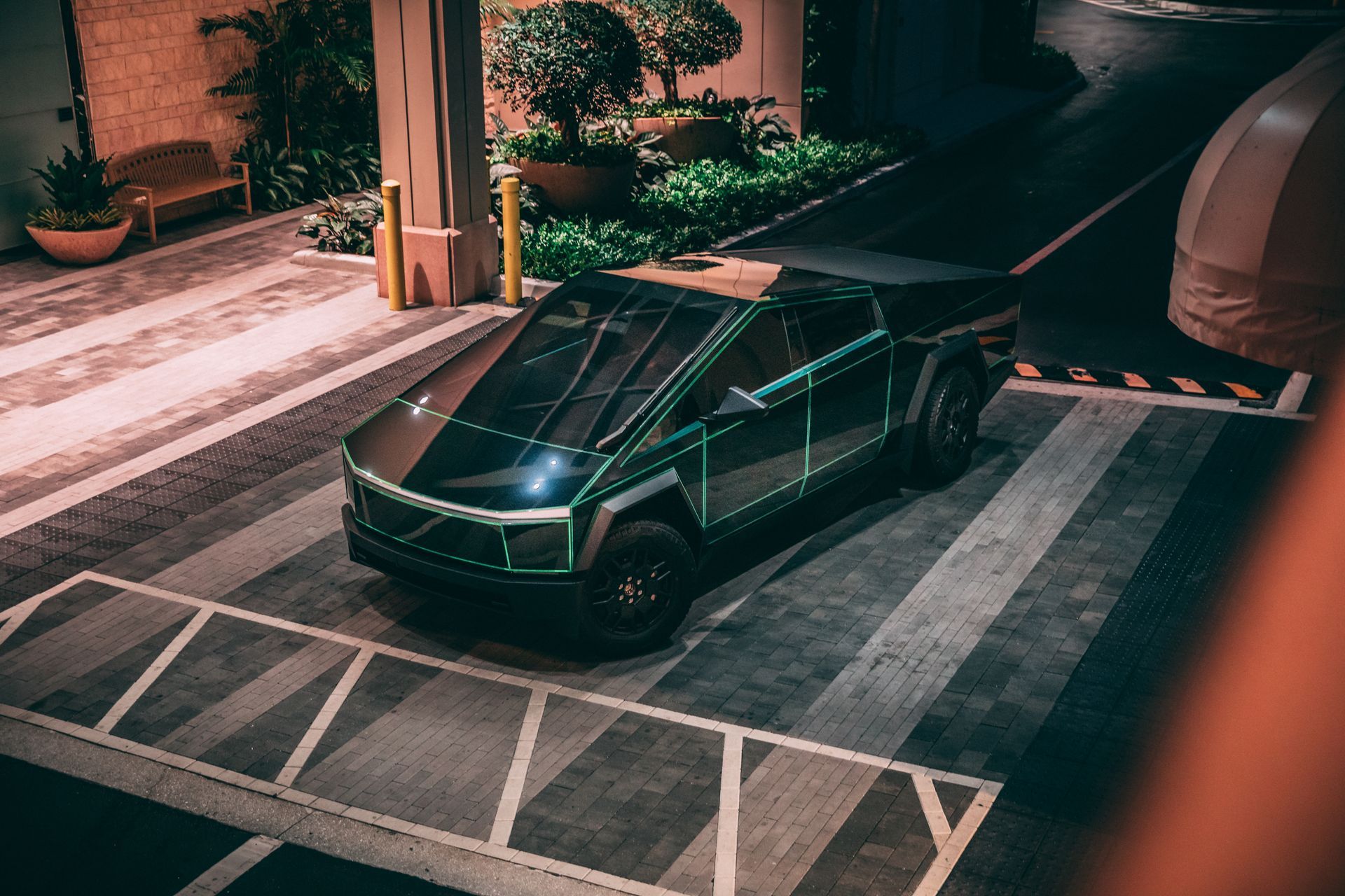 Tesla Cybertruck parked in a parking structure with neon green accents and black wheels.