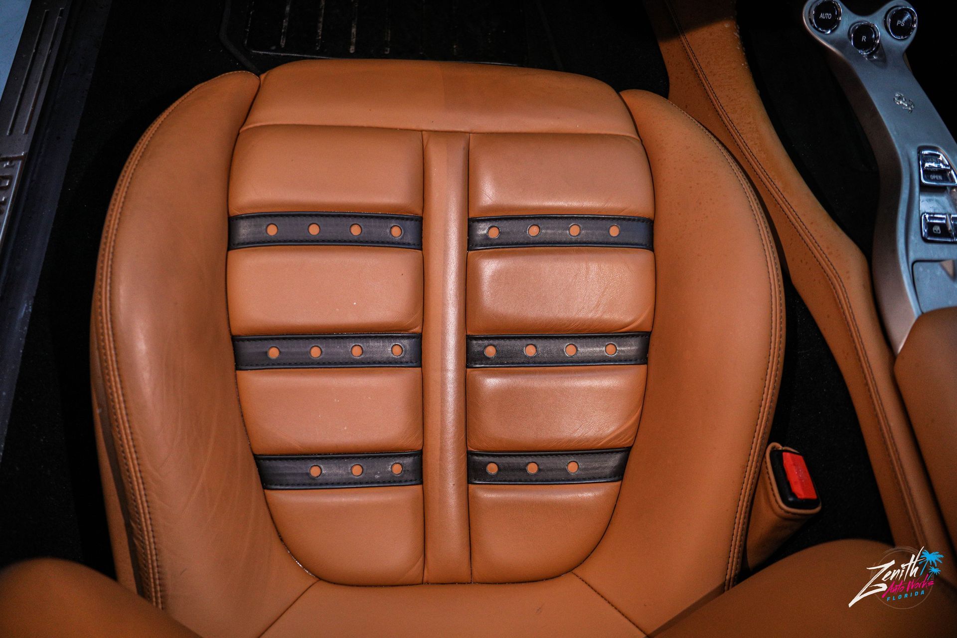 Tan leather car seat with black accents and stitching.