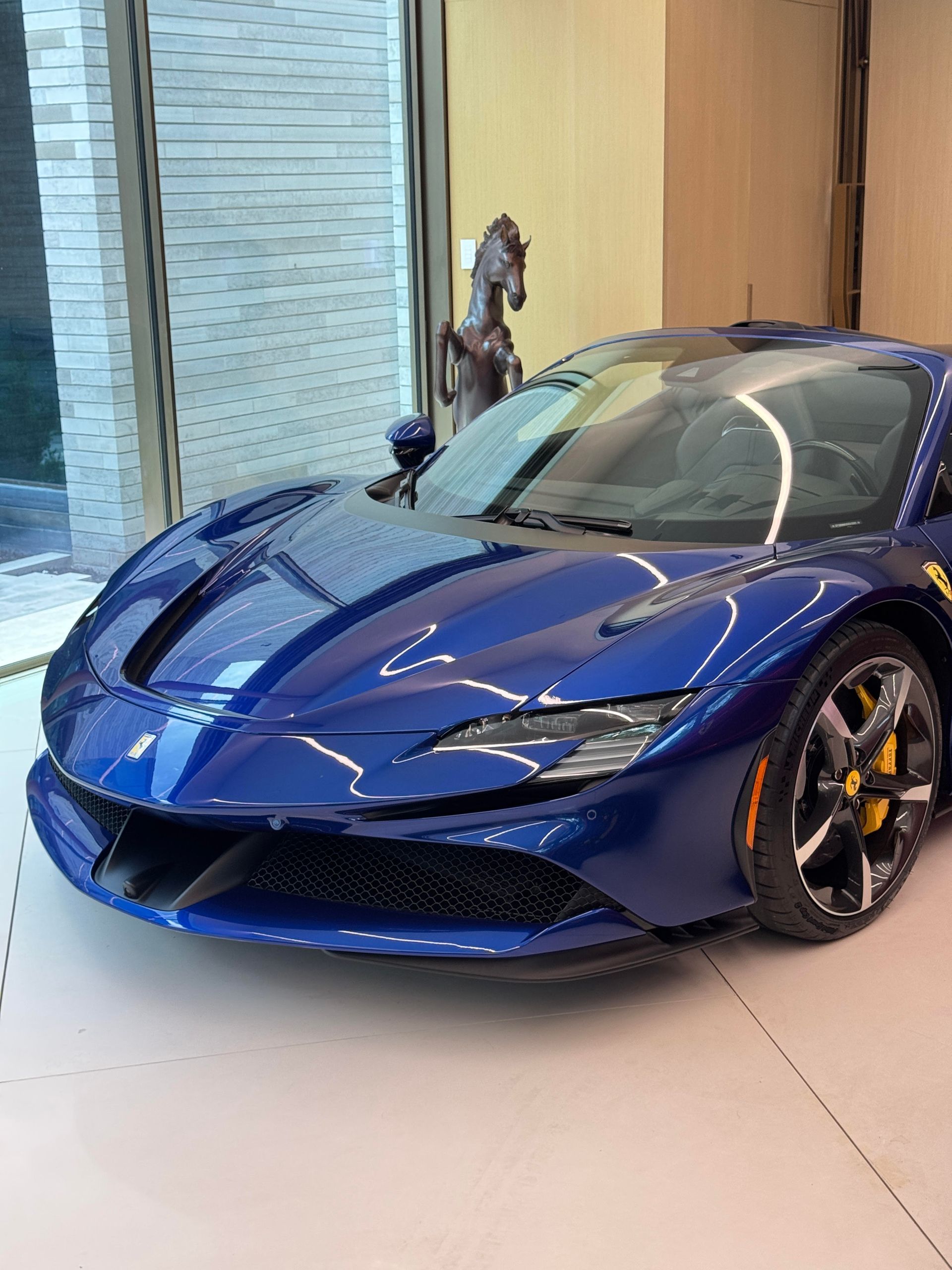 Blue Ferrari sports car parked inside showroom.