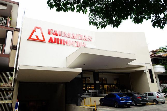 Una farmacia con coches aparcados delante.