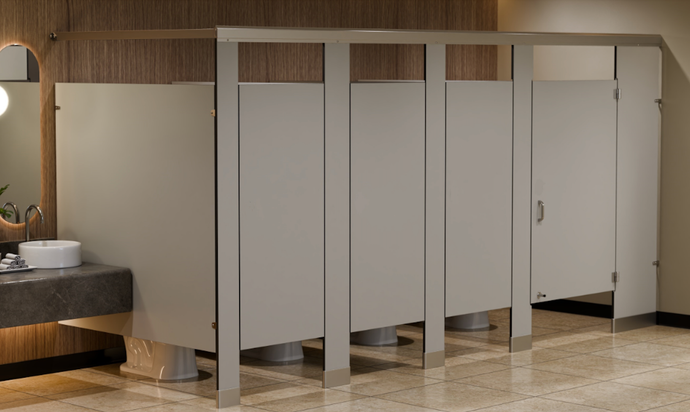 Cabina de aseo con puertas grises cerradas y mamparas metálicas en un baño público alicatado.