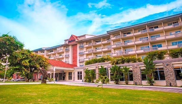 Un gran hotel con muchos balcones está rodeado de árboles y césped.