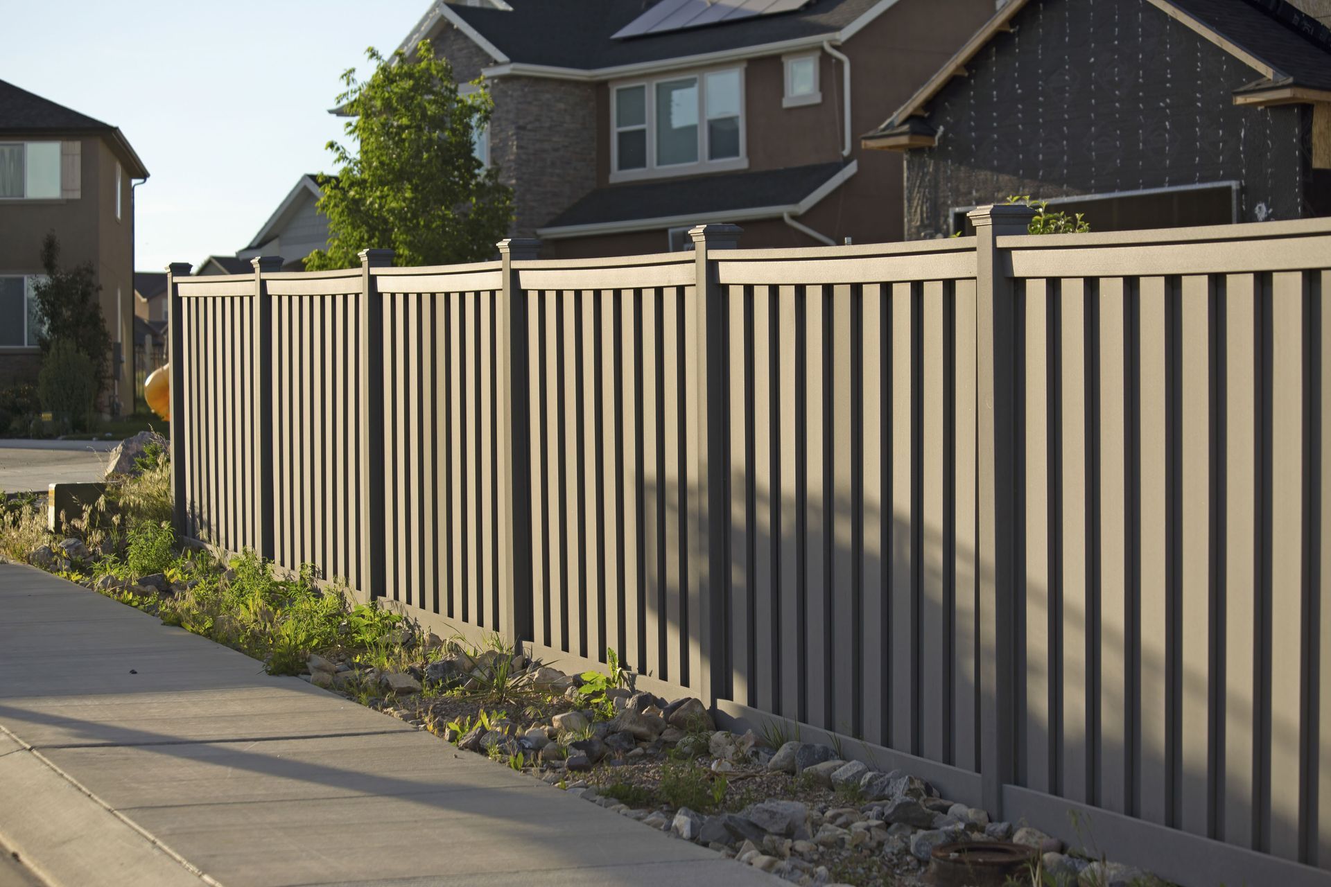 A fence along a sidewalk with a house in the background