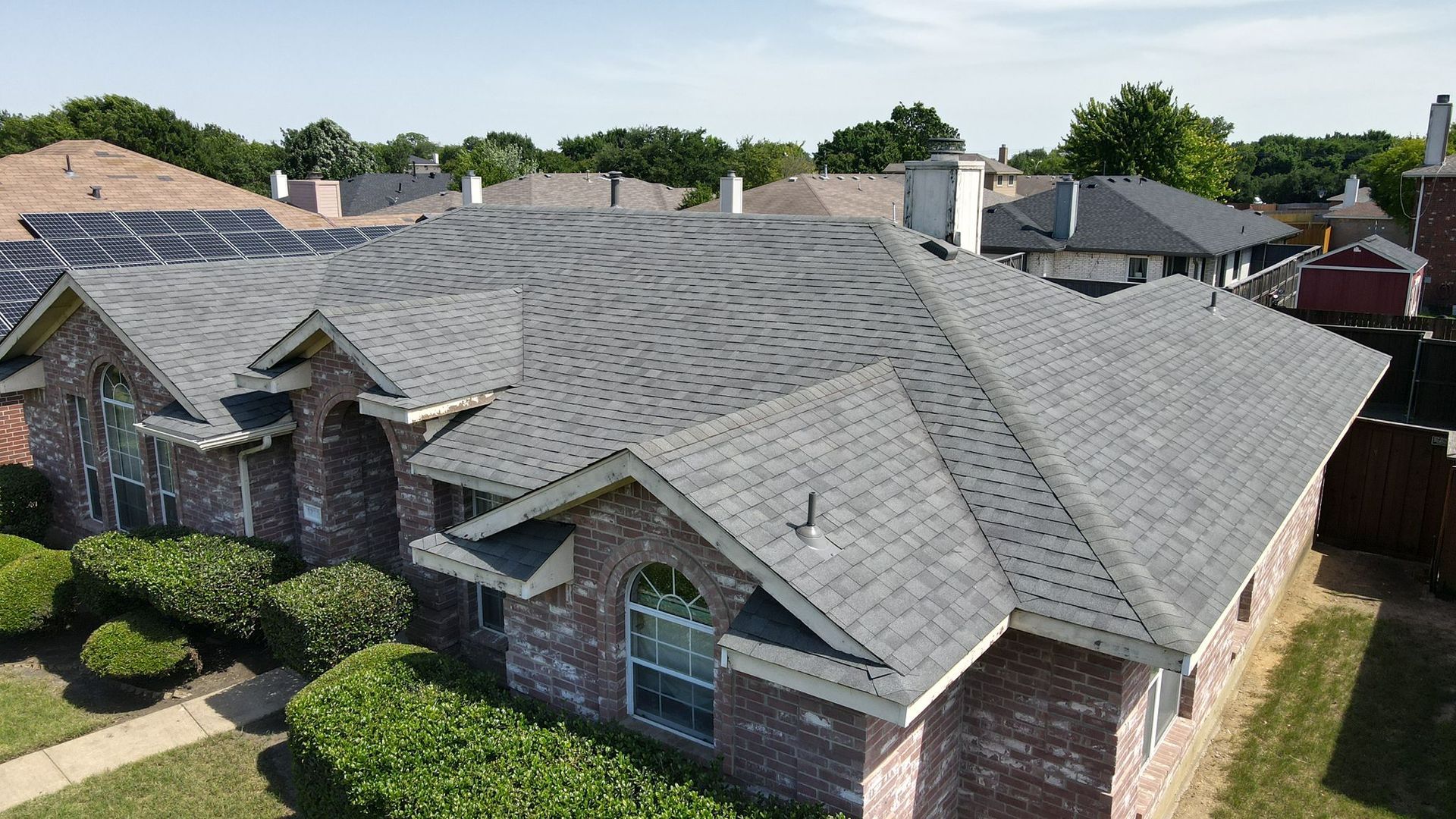 An aerial view of a brick house with a new roof.