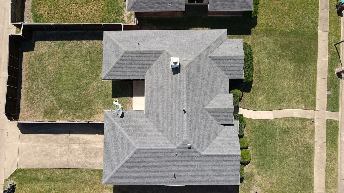 An aerial view of a house with a roof in a residential area.